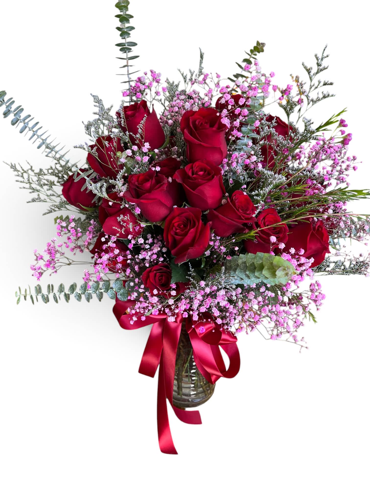 Red roses in a glass vase with pink filler flowers and a red ribbon