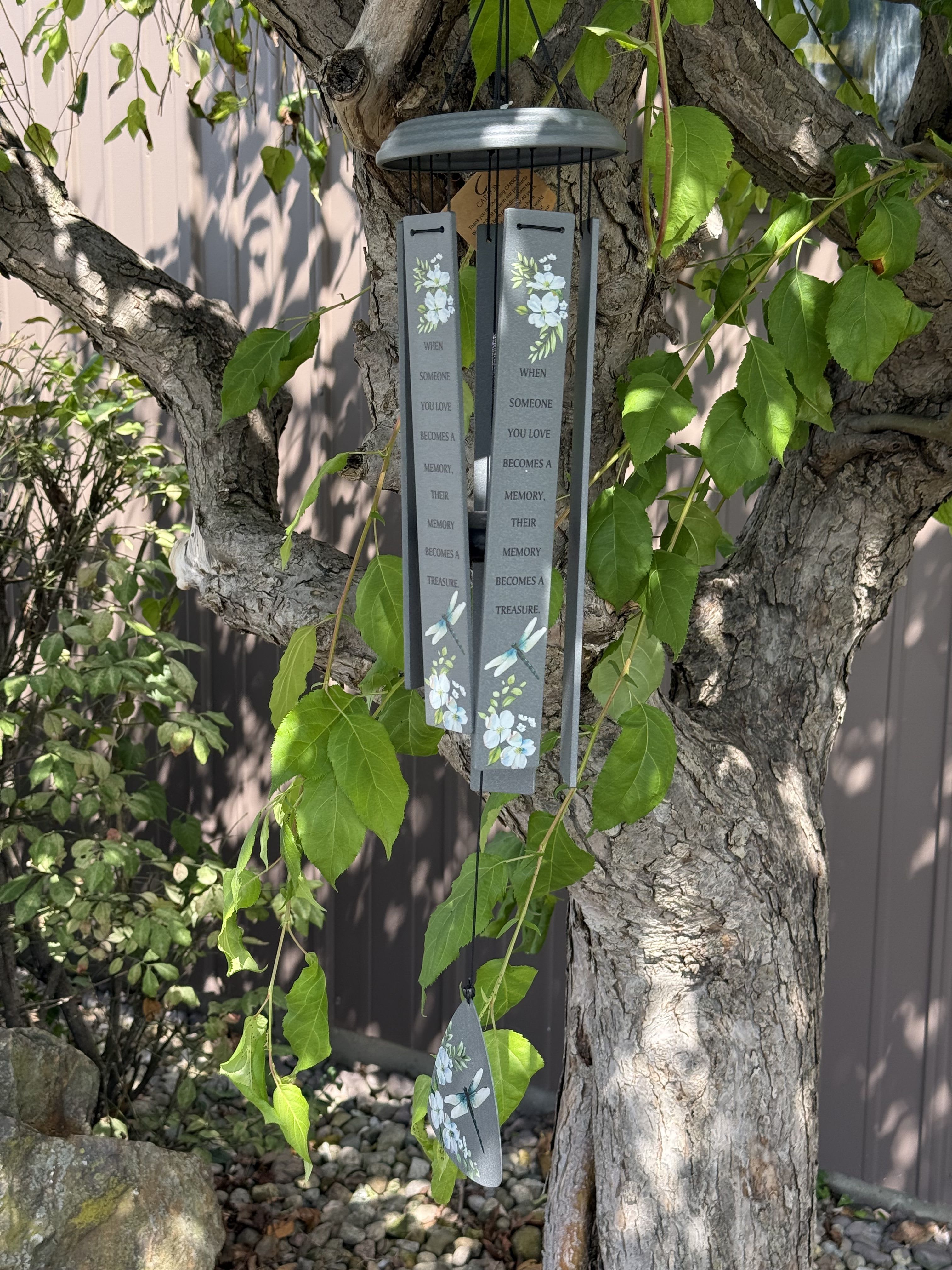 Gray memorial wind chime hanging from a tree with floral accents