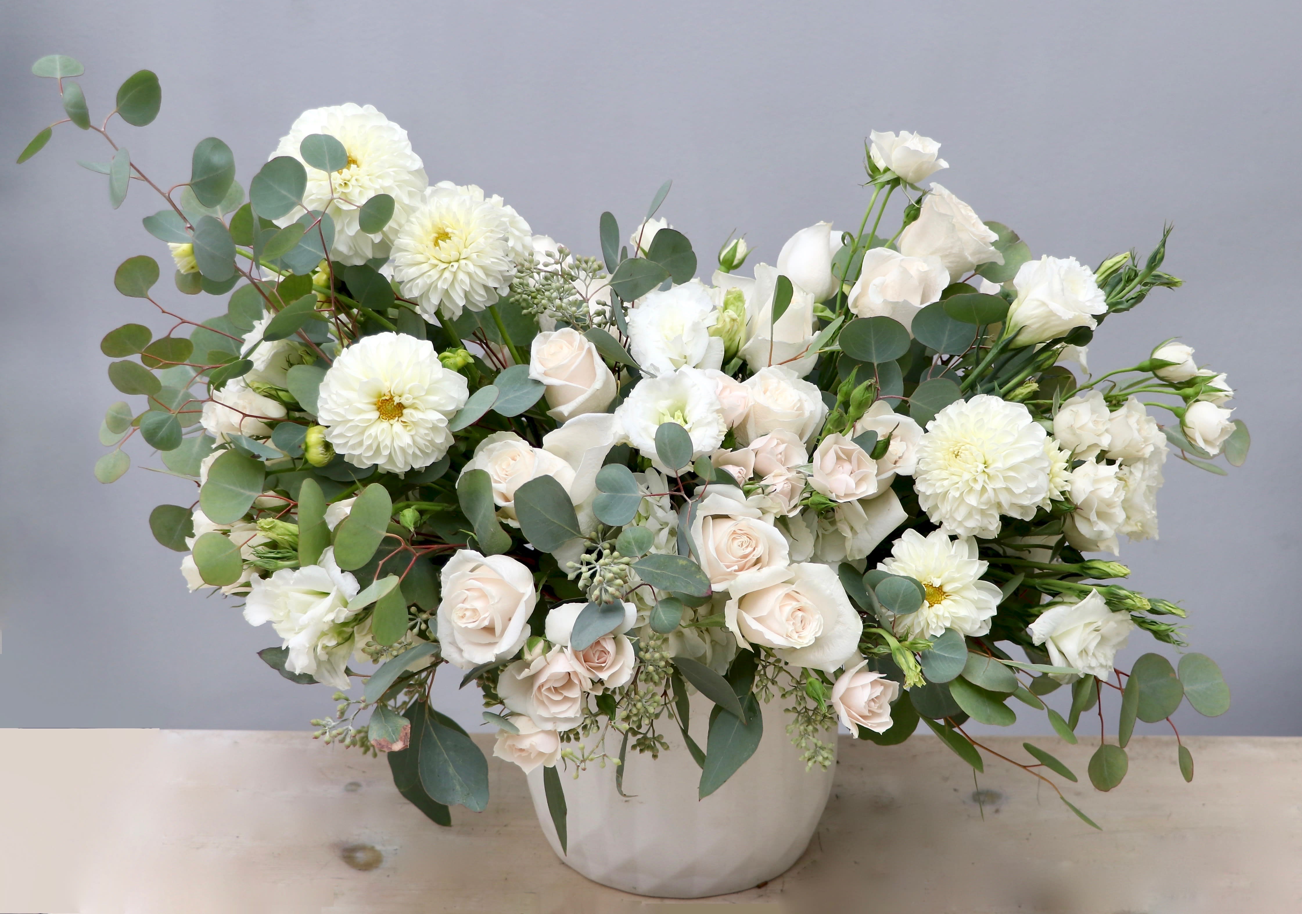 Large white and cream flower arrangement in a white ceramic vase
