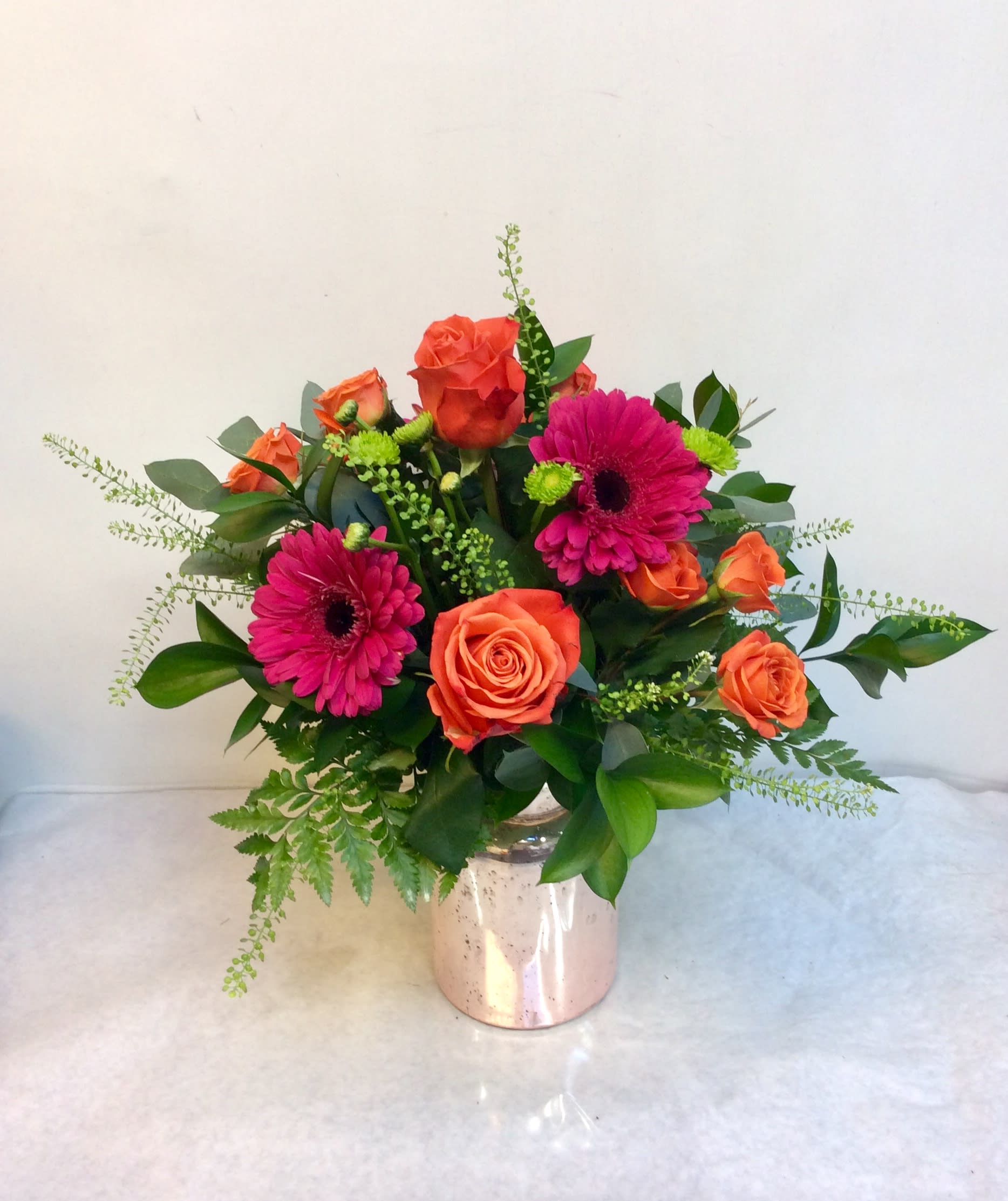 Bouquet of orange roses and pink gerbera daisies in a metallic vase