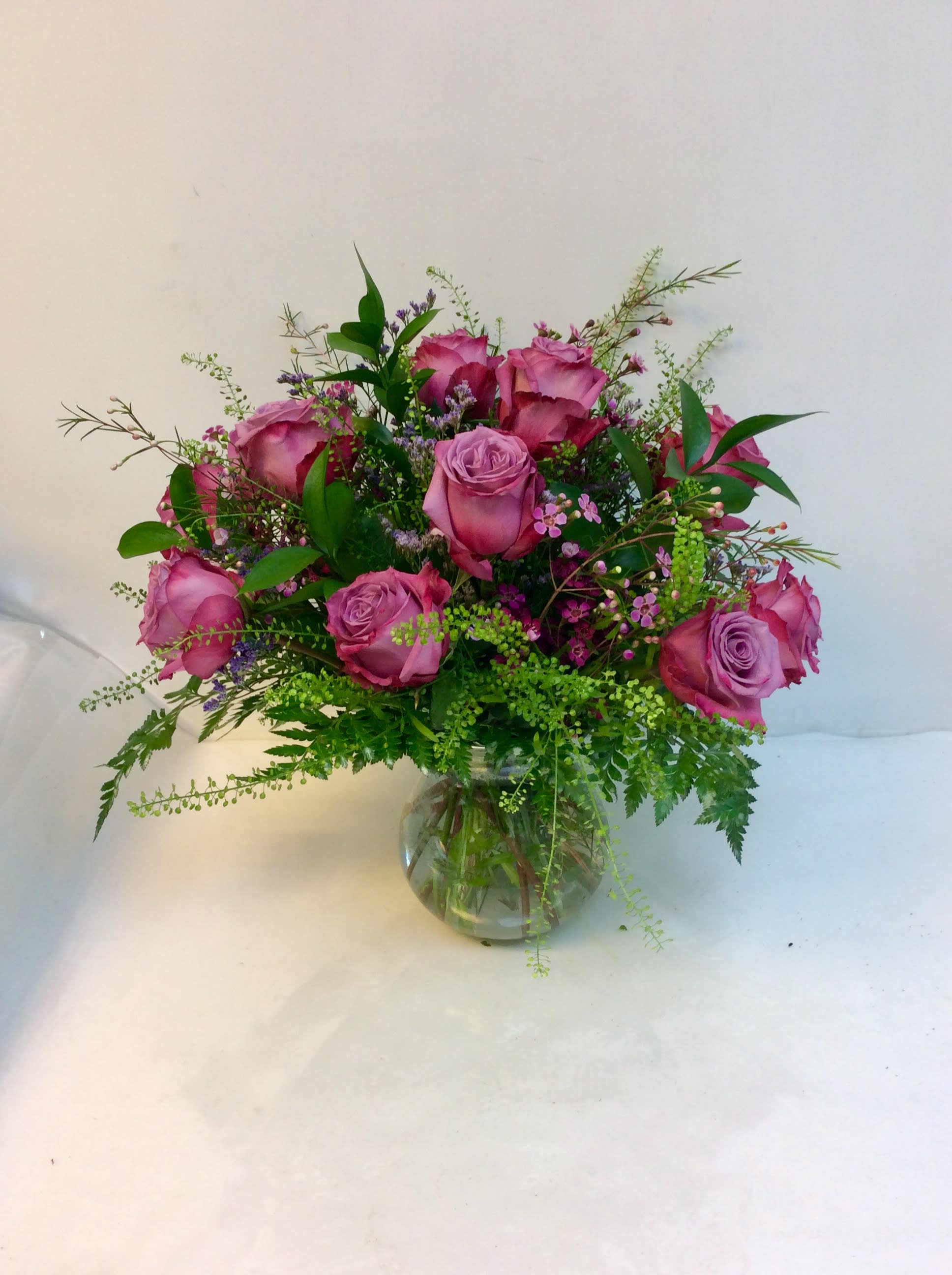 Pink roses arranged in a clear glass vase with mixed greenery