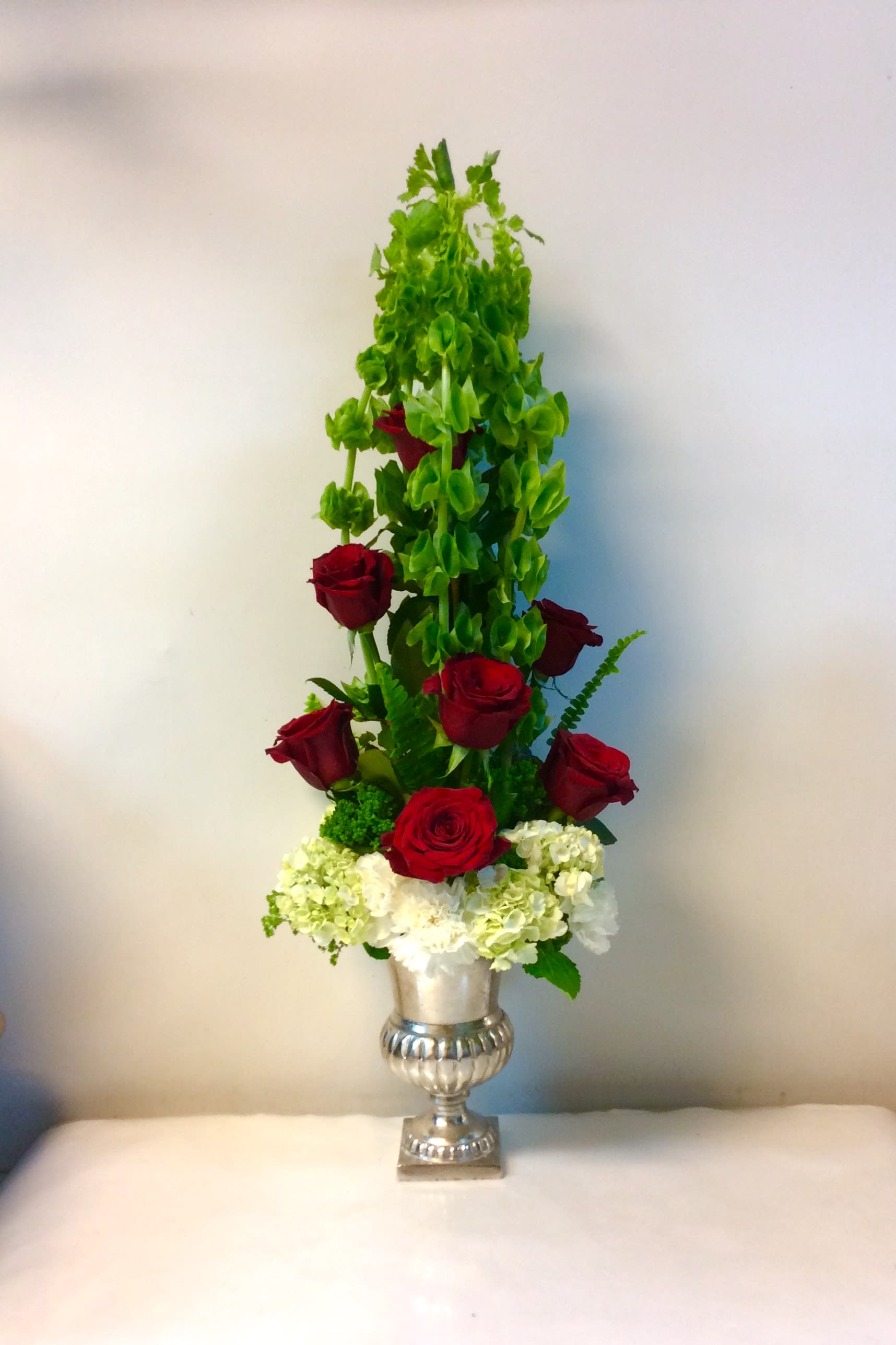 Tall red rose arrangement in a silver urn with white hydrangeas