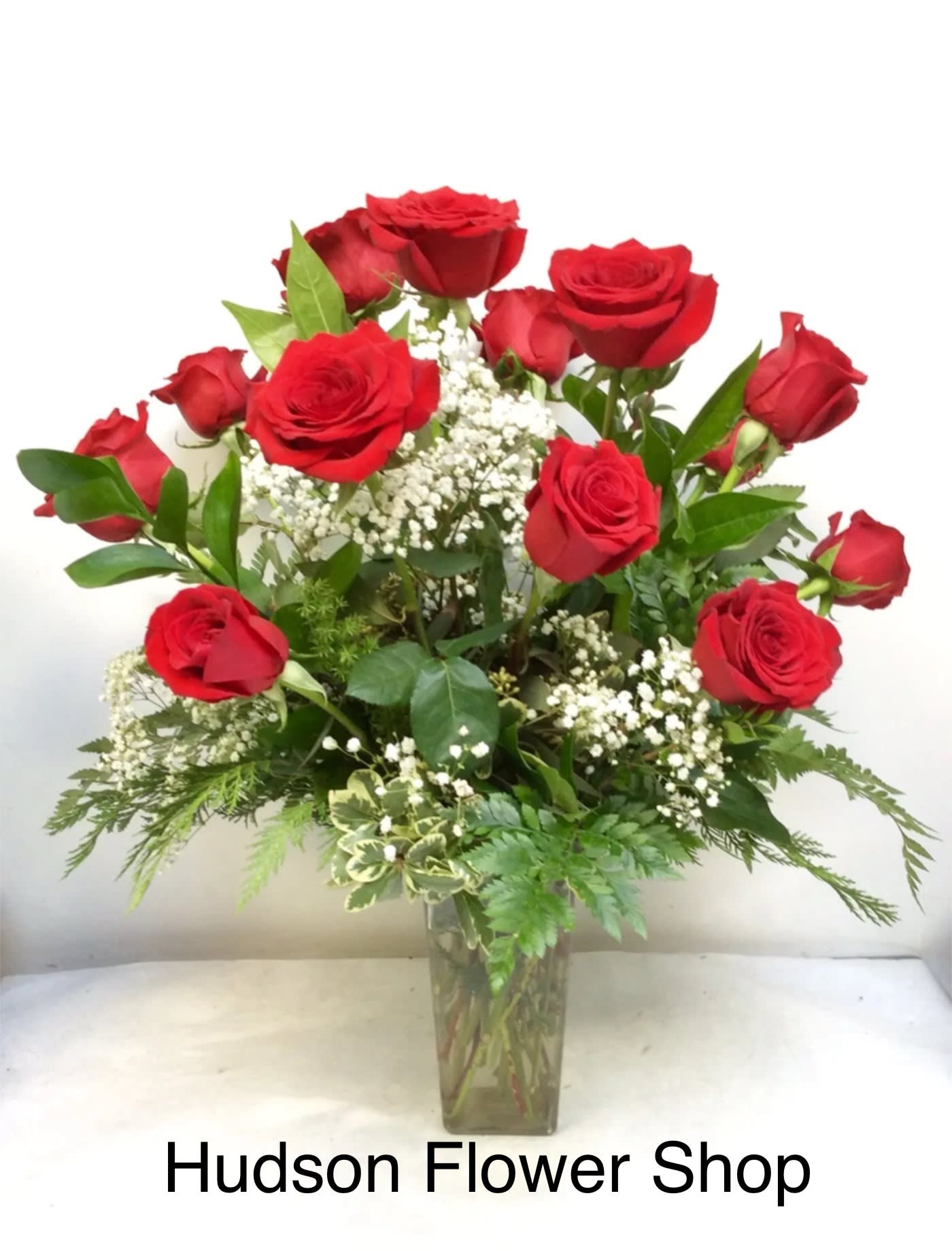 Red roses arranged in a clear glass vase with white filler flowers