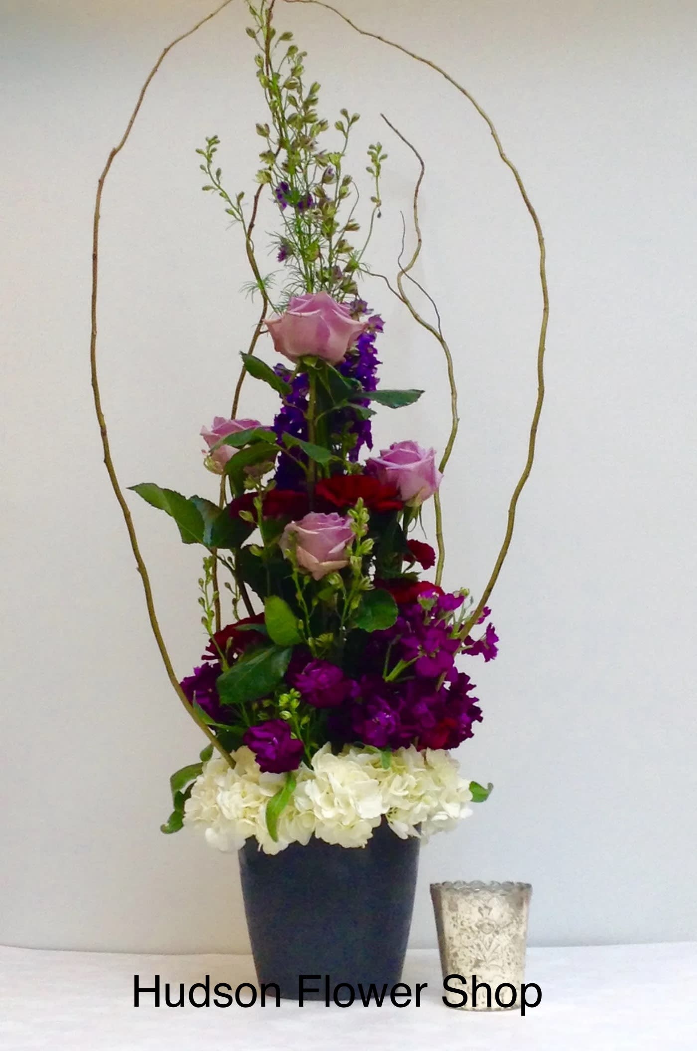 Tall floral arrangement with pink and red roses in a black vase