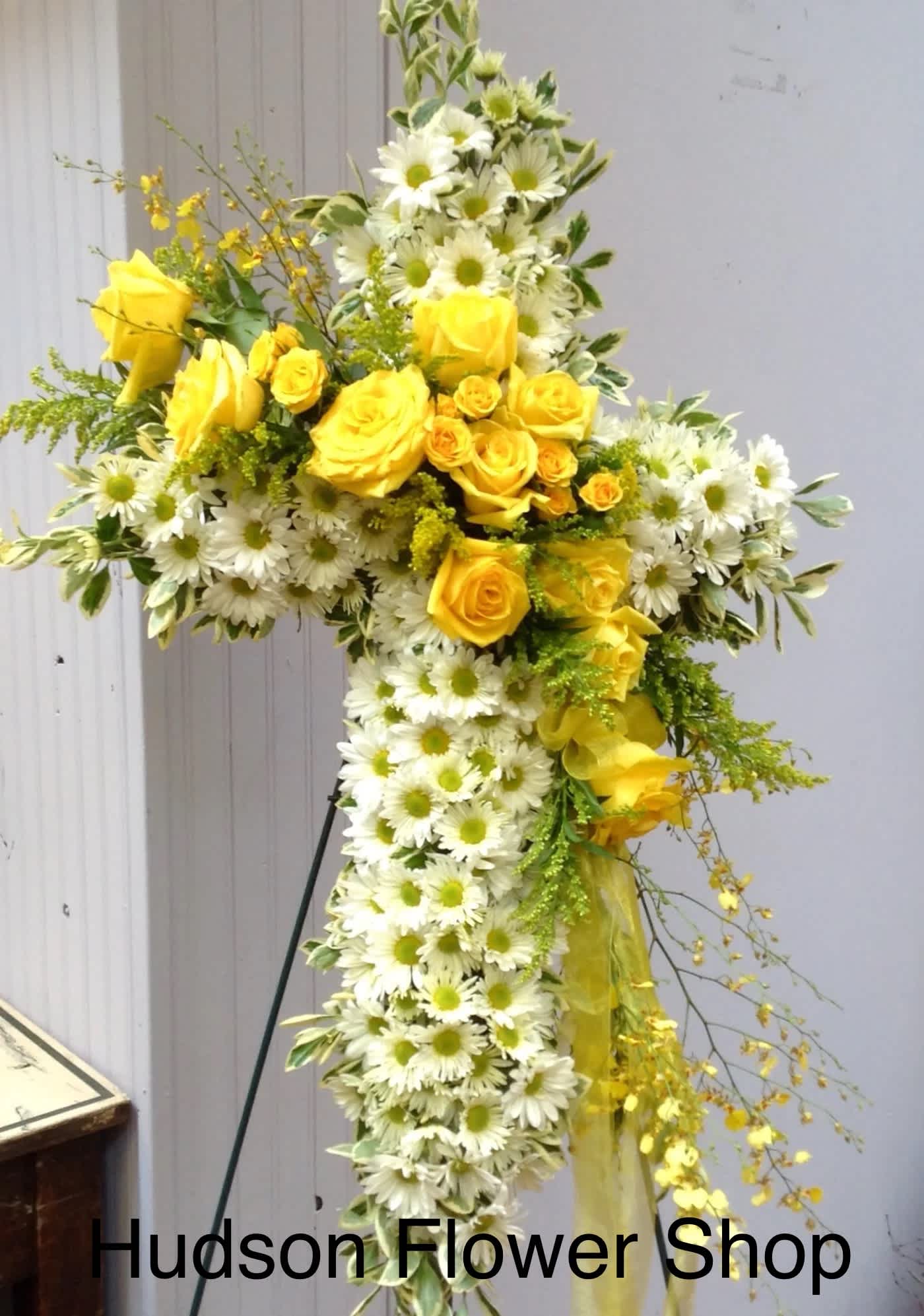 Yellow roses and white daisies arranged in a cross-shaped floral tribute