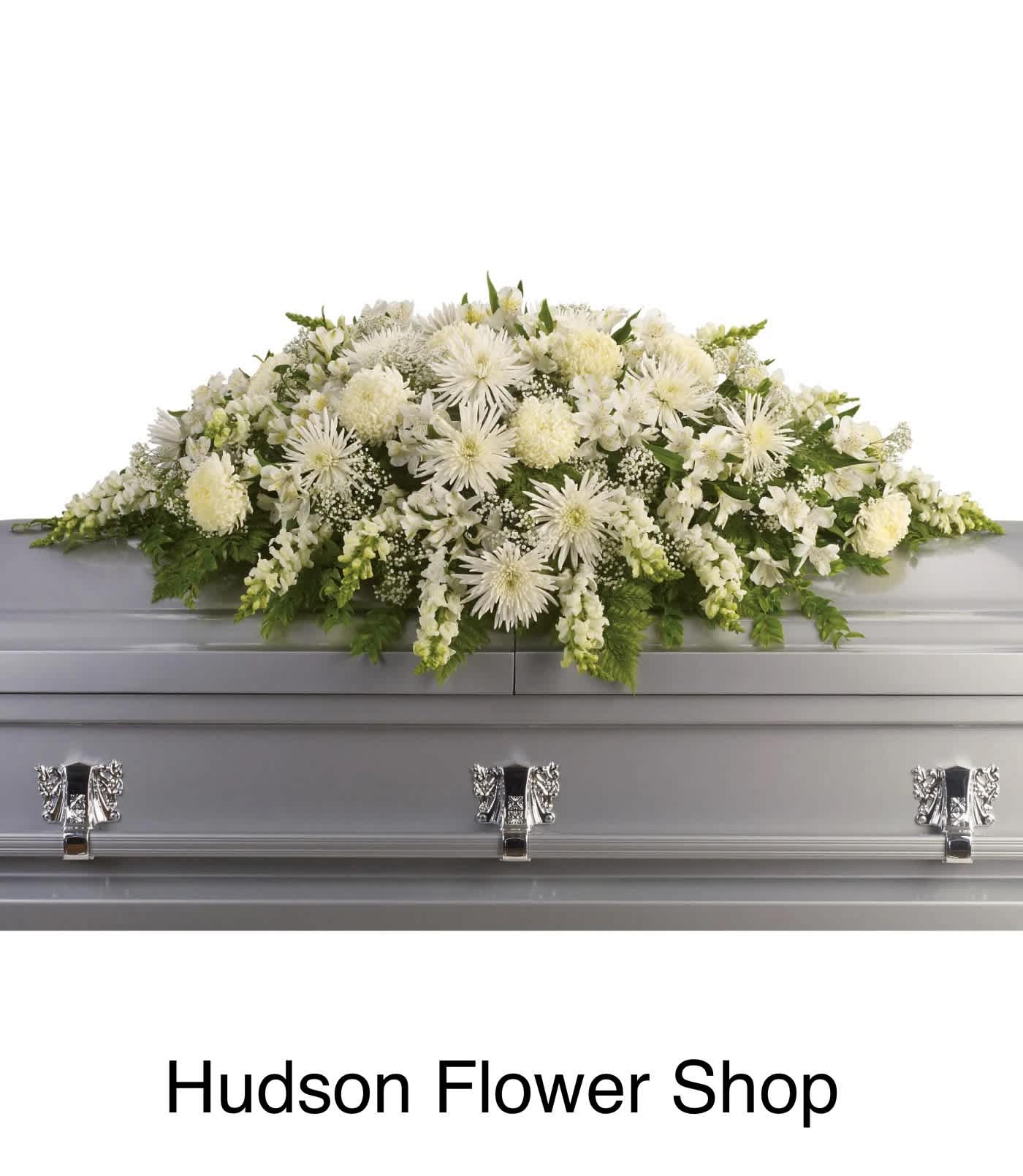 White floral casket spray on a gray coffin