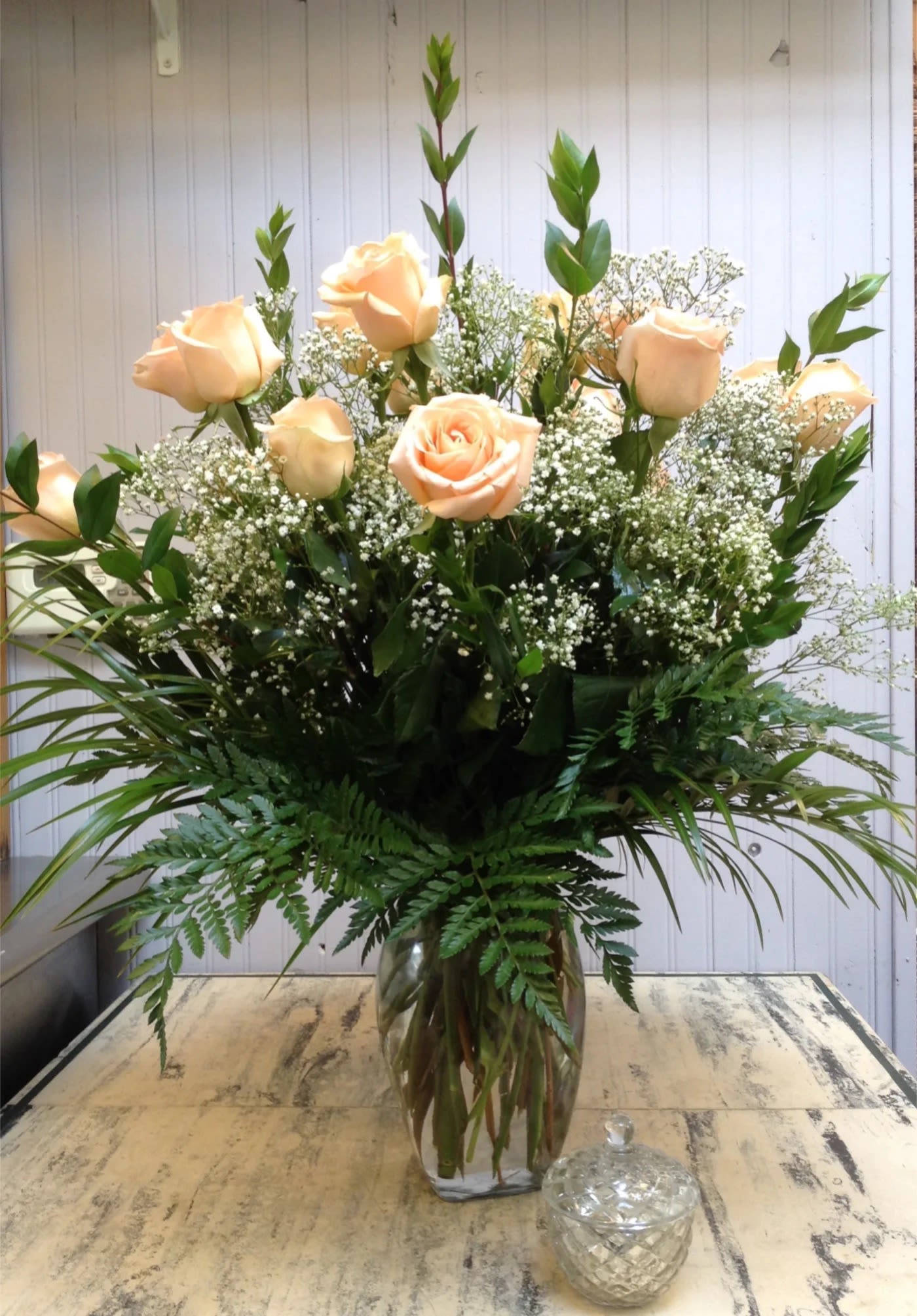 Peach roses in a clear glass vase with baby's breath and greenery