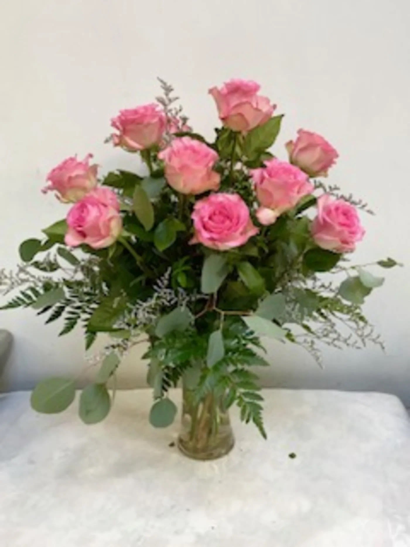 Pink roses arranged in a clear glass vase with greenery