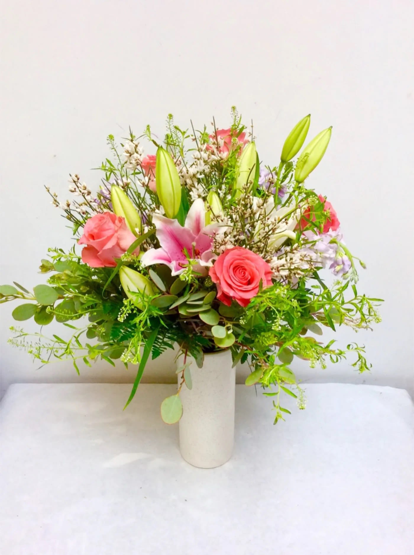 Pink roses and lilies arranged in a white vase
