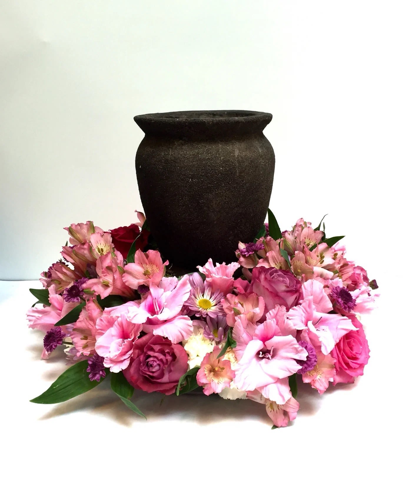 Pink floral arrangement around a dark urn-shaped vase