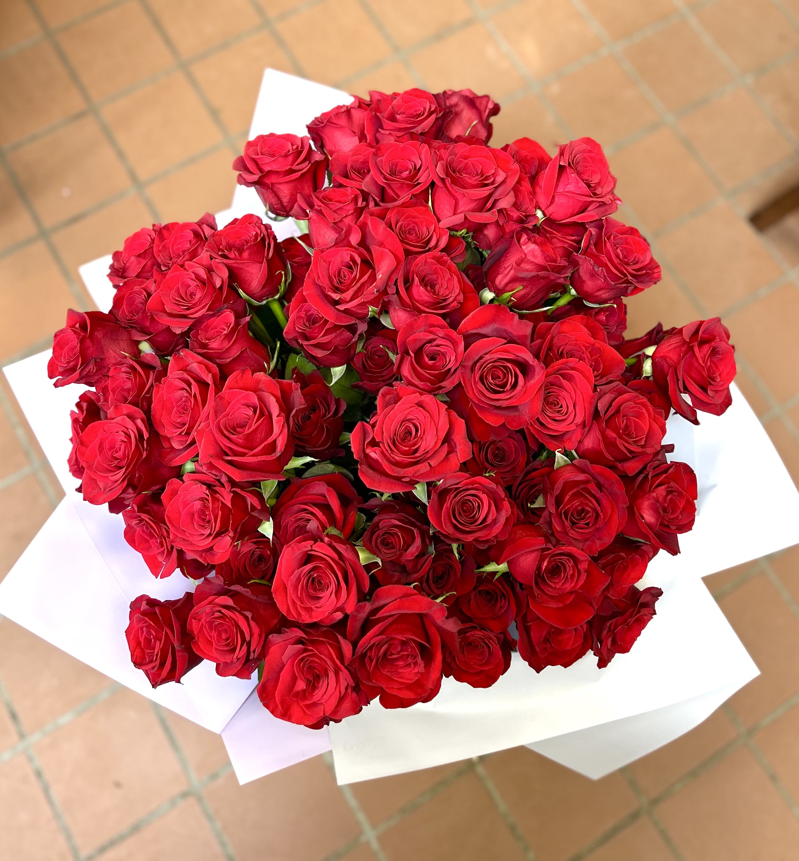 Large bouquet of red roses wrapped in white paper