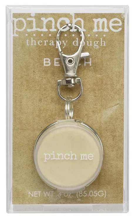 Packaged keychain with a round cream charm and metal clip