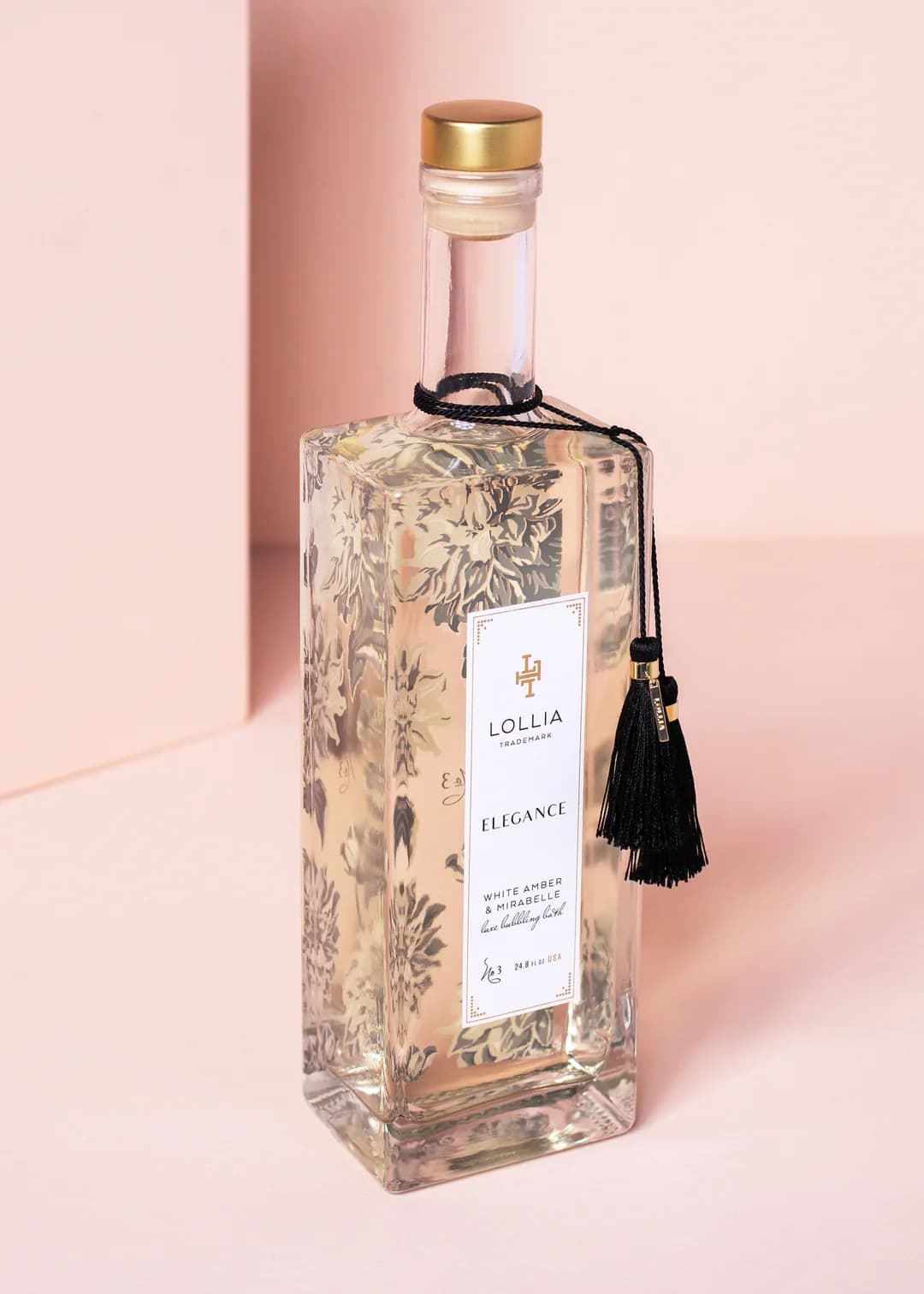 Clear glass bottle with gold cap and black tassel label