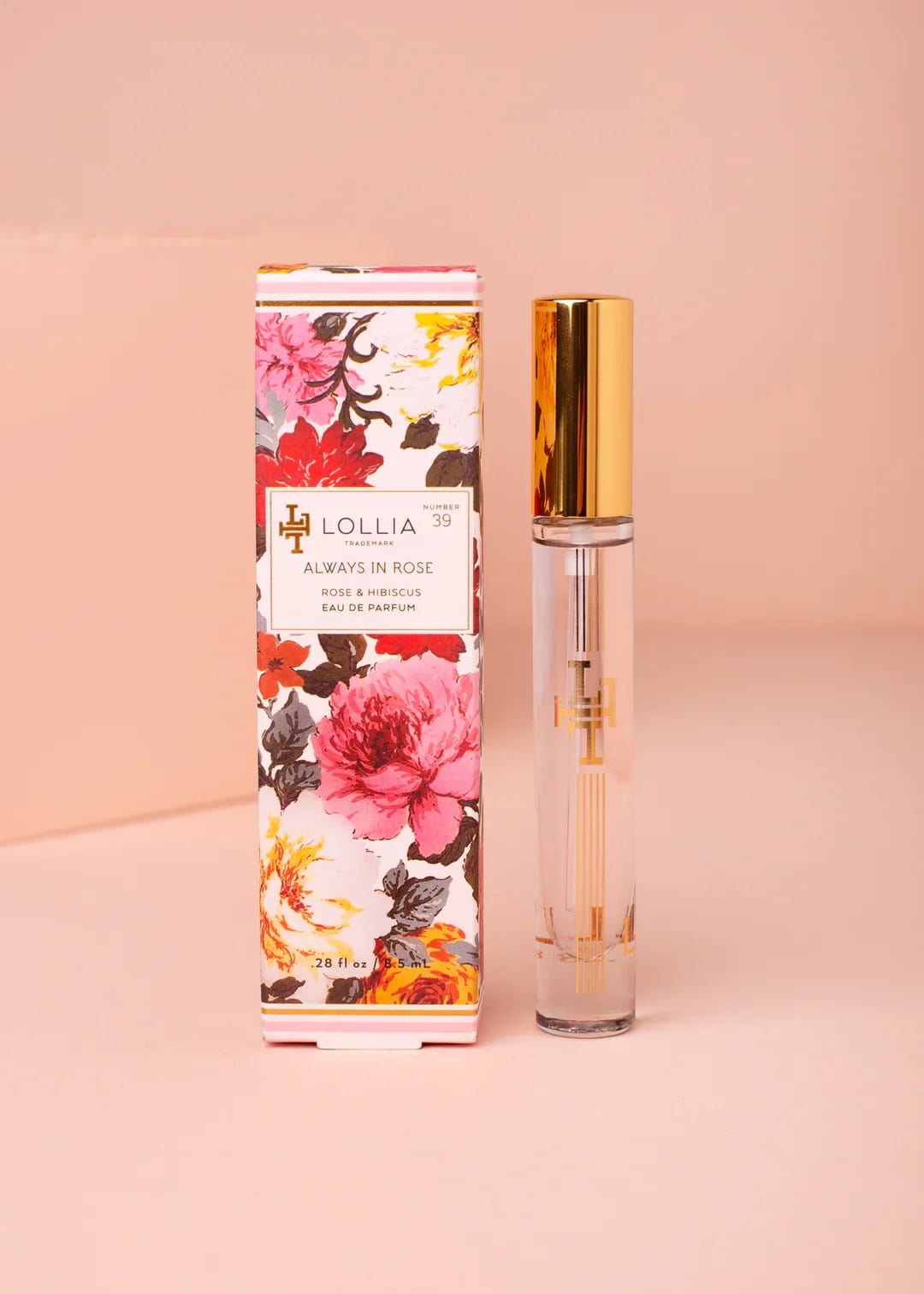 Floral-print perfume box beside a clear glass perfume bottle with a gold cap