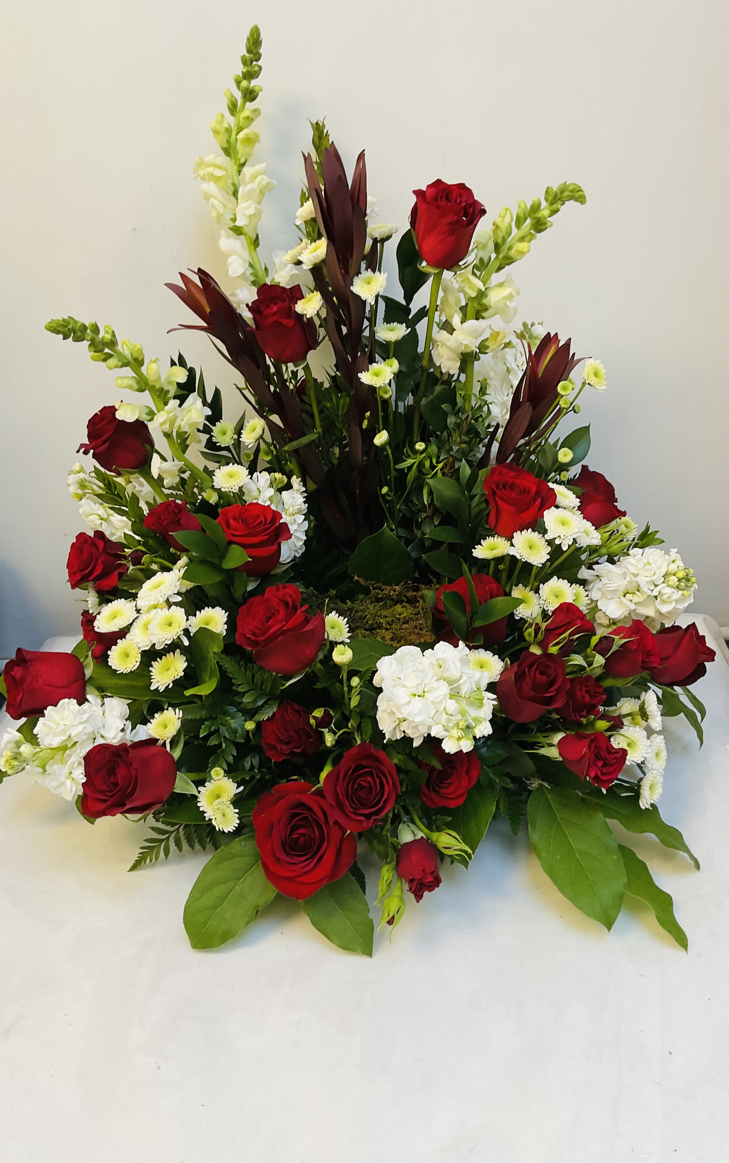 Red roses and white flowers in a large tiered arrangement