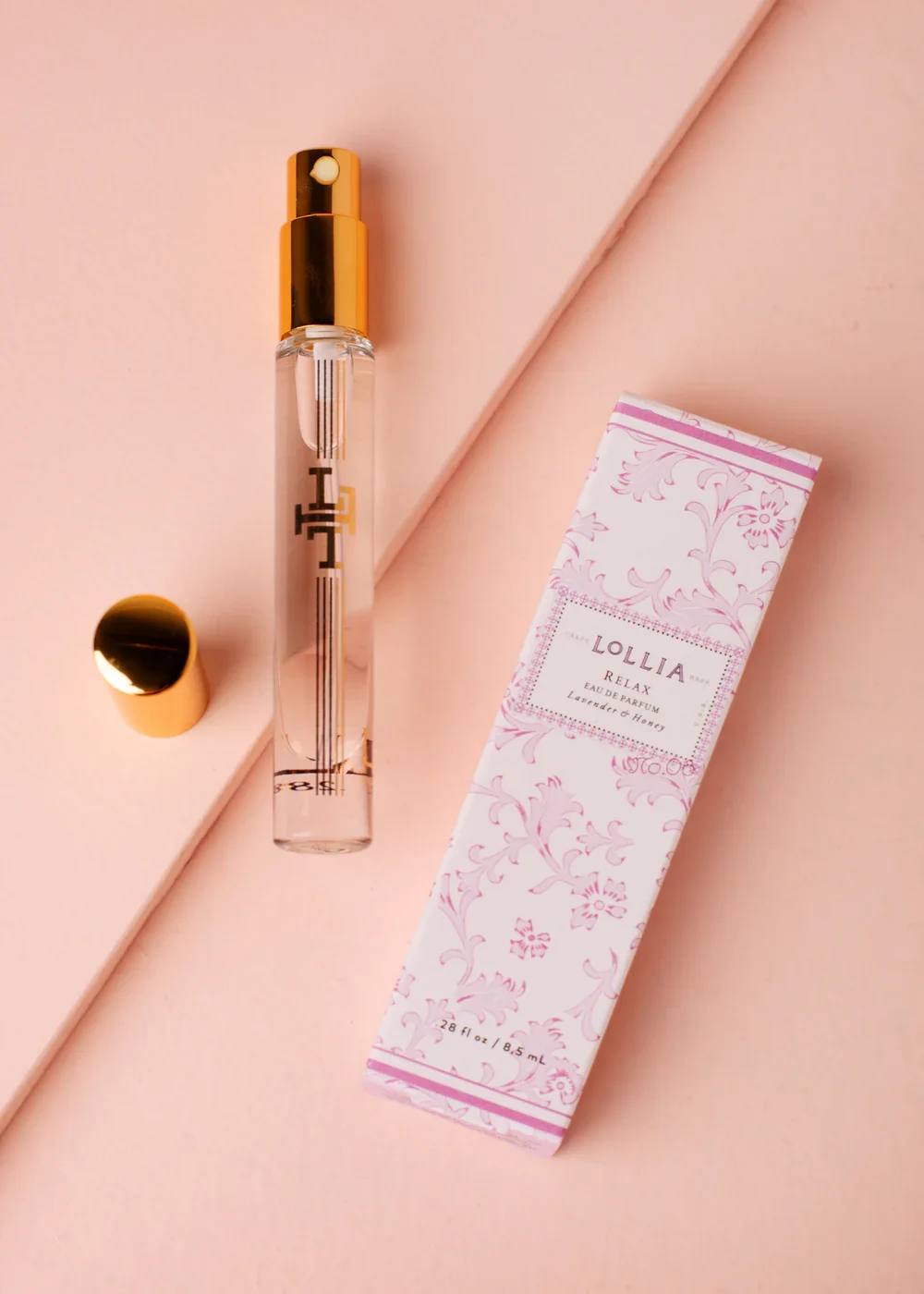 Perfume spray bottle with a pink patterned box on a blush background