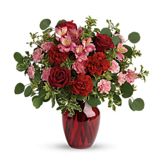 Blooming Belles Bouquet - Tres belle! Ruby red roses and delicate pink alstroemeria are mixed with whimsical greens in a radiant vase for a beautifully blooming gift she'll never forget! Red roses, pink alstroemeria, red carnations, and pink miniature carnations are accented with silver dollar eucalyptus and pitta negra. Delivered in a ruby rose vase. 
