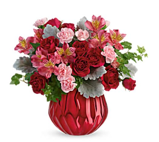 Red roses and pink flowers in a red glass vase