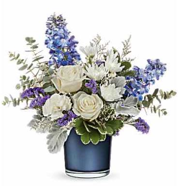 Sapphire Bliss Bouquet - Tranquil blues! This lovely crème rose bouquet resembles fluffy white clouds against a clear blue sky, elegantly paired with a sapphire blue glass vase that shimmers with a pearlescent finish.  This arrangement features crème roses, blue delphinium, white carnations, white cushion spray chrysanthemums, blue sinuata statice, and purple limonium, accented with dusty miller, spiral eucalyptus, and variegated pittosporum. It is beautifully delivered in Teleflora's Polished Gem Vase (while supplies last).