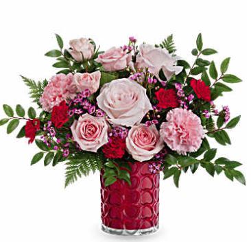 Pink and red roses with carnations in a red glass vase