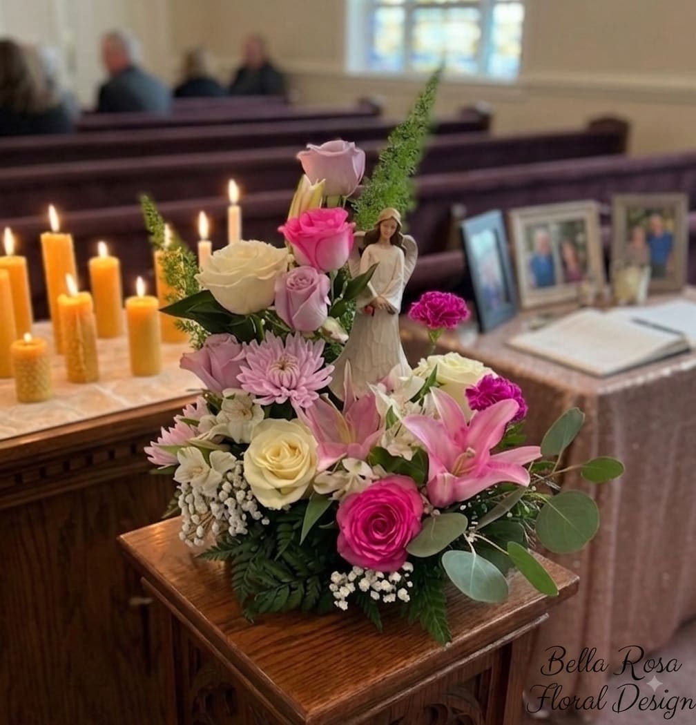 Pink and white floral arrangement with candles and a small angel figurine