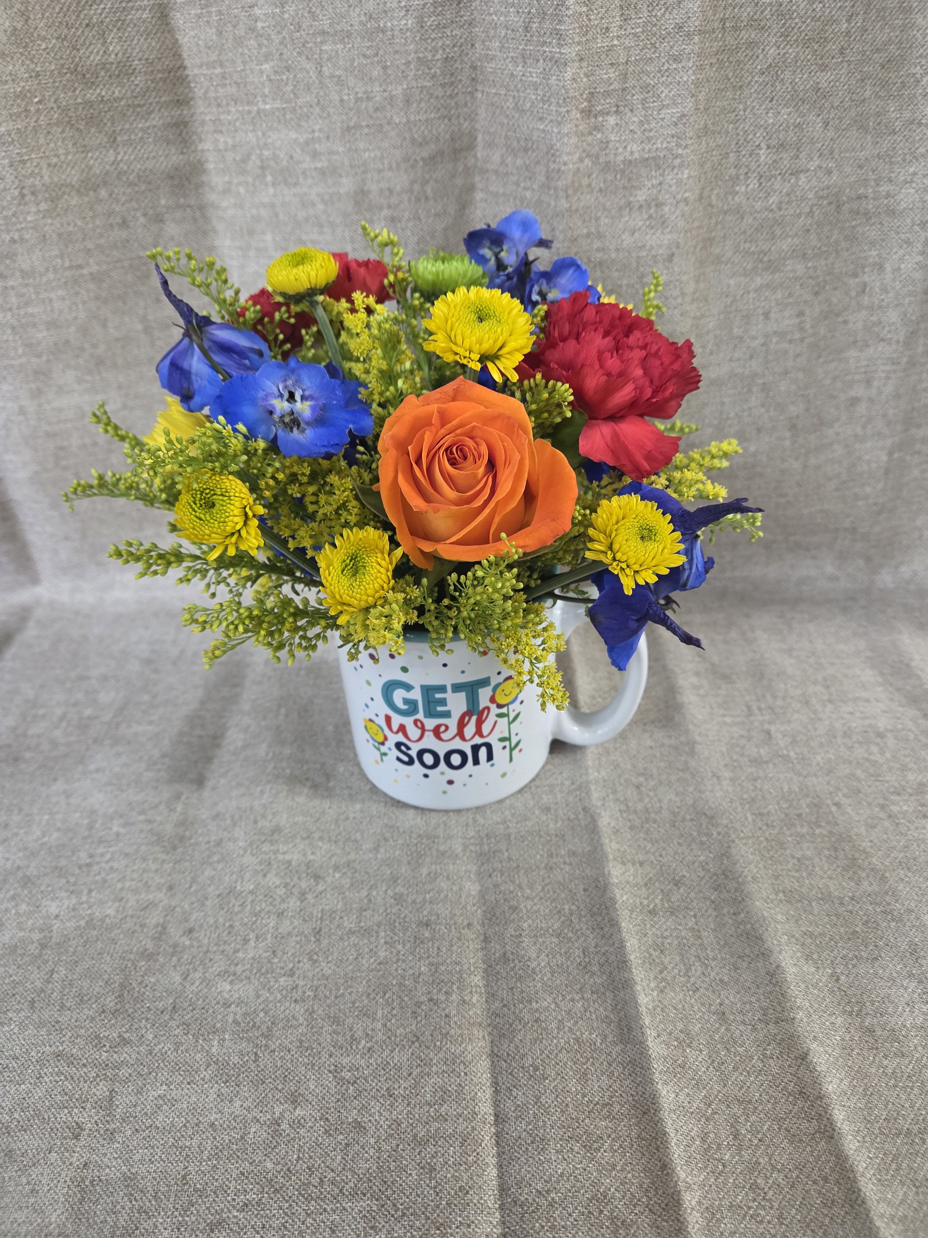 Get Well Flower Mug - Brighten someone's day with our charming Get Well Mug with Fresh Floral Arrangement. Thoughtfully designed to bring comfort and cheer, this keepsake "Get Well" mug is filled with a beautiful selection of fresh, seasonal blooms arranged by our expert florists. Featuring vibrant colors and delicate textures, this gift is the perfect way to send warm wishes, encouragement, and a smile during recovery.