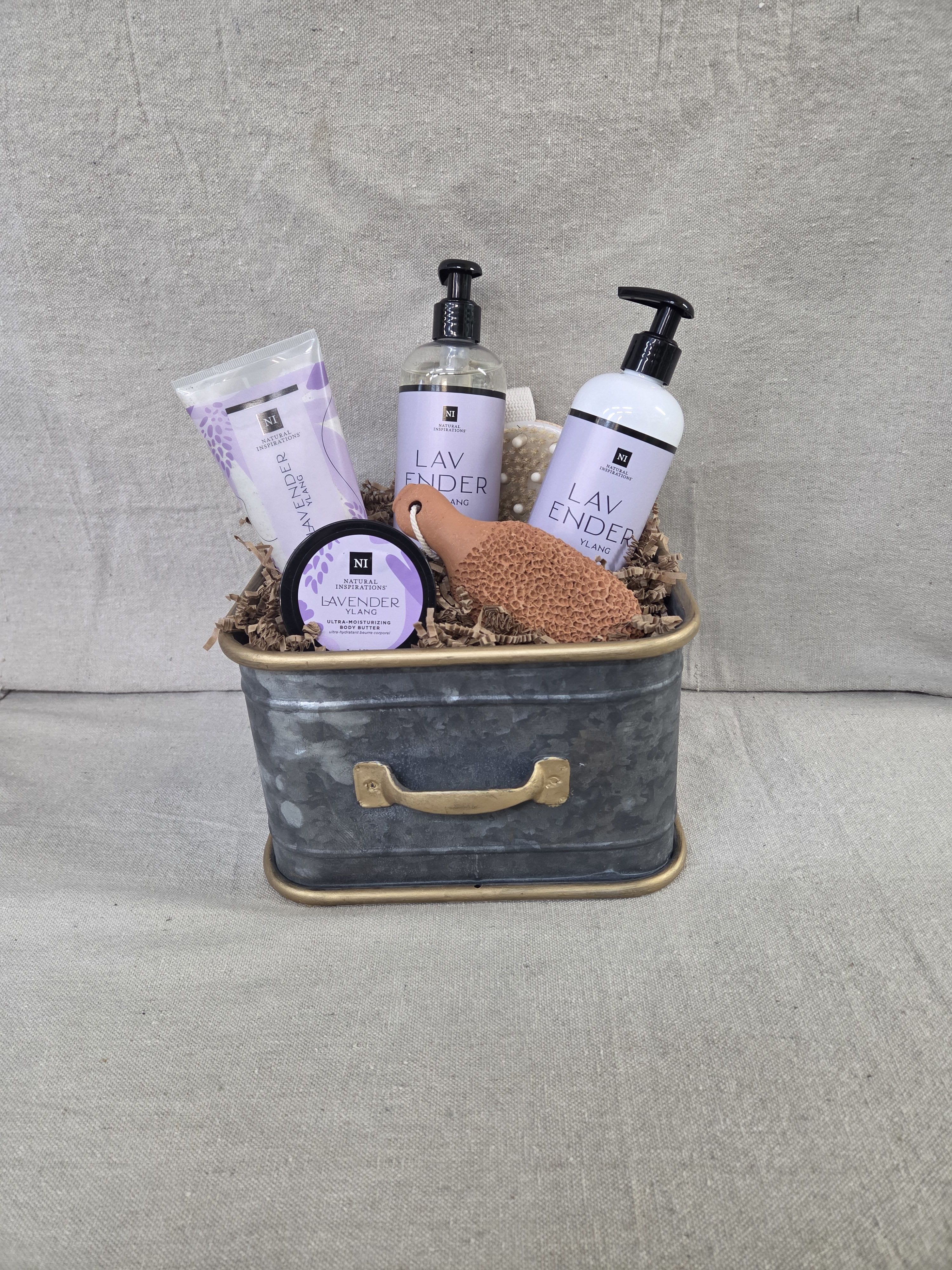 Lavender-scented bath and body gift set in a metal tin with bottles, tube, jar, and sponge