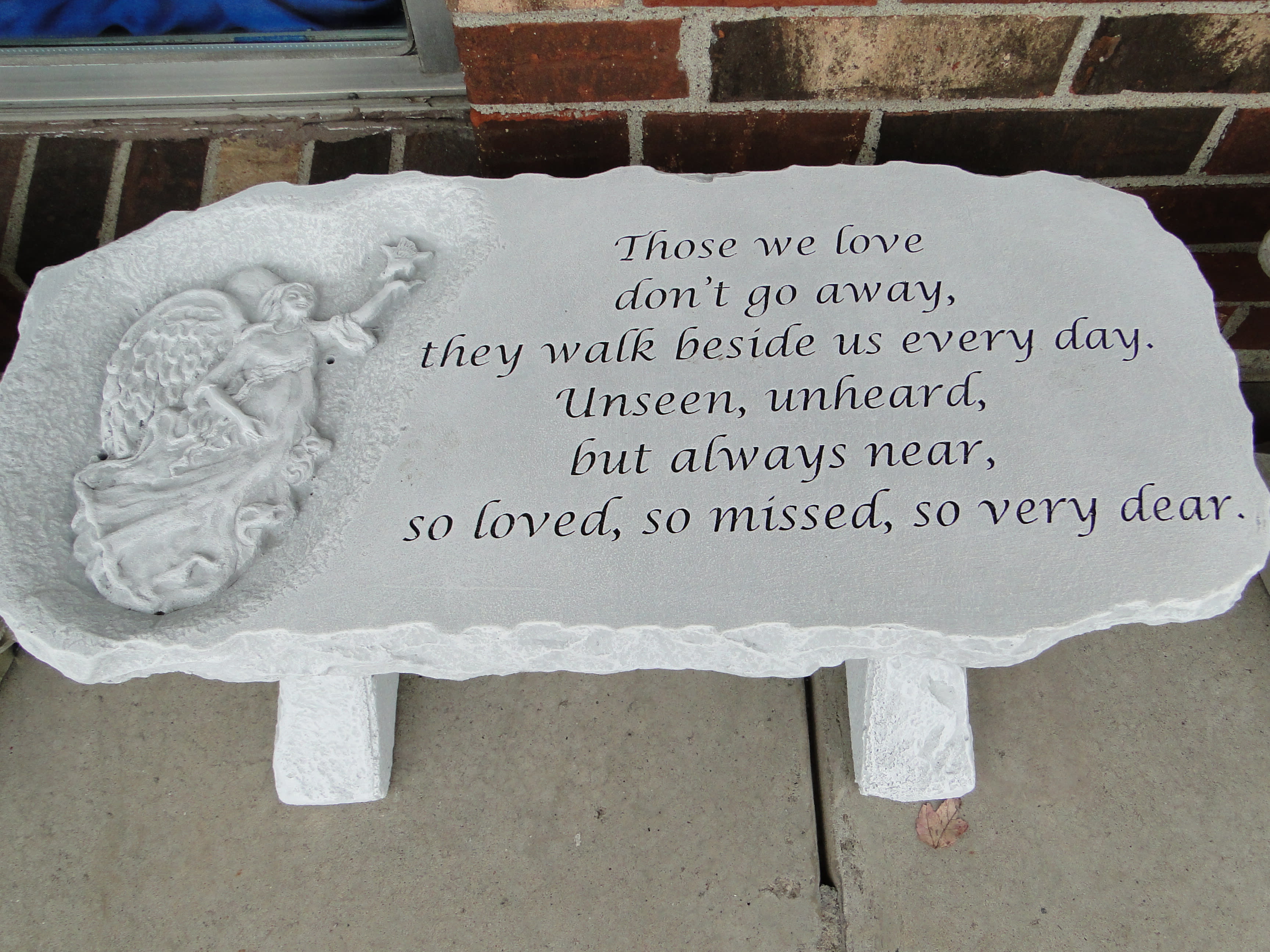 White memorial stone with an angel relief and engraved sympathy verse
