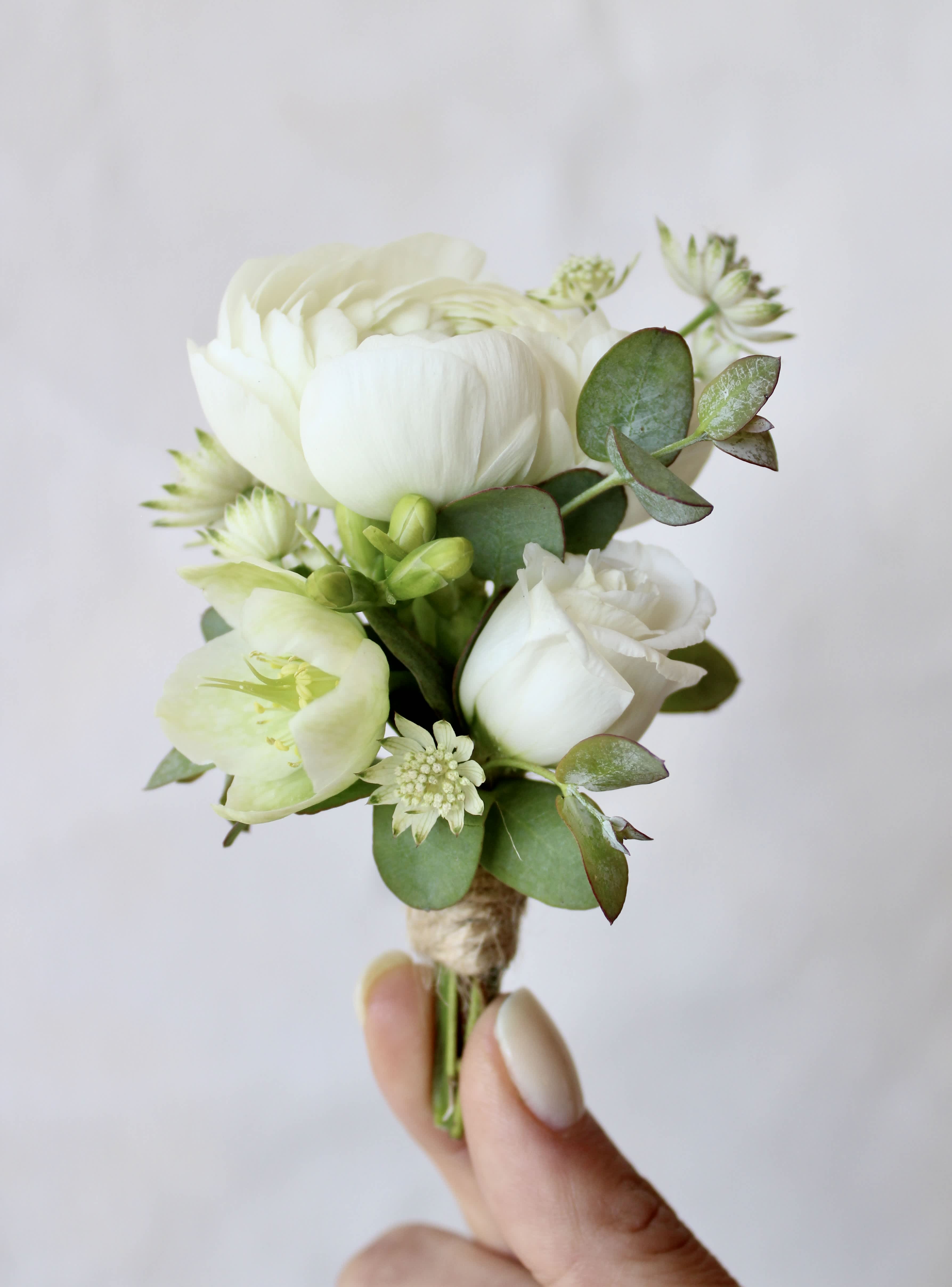 Small white flower boutonniere with green foliage