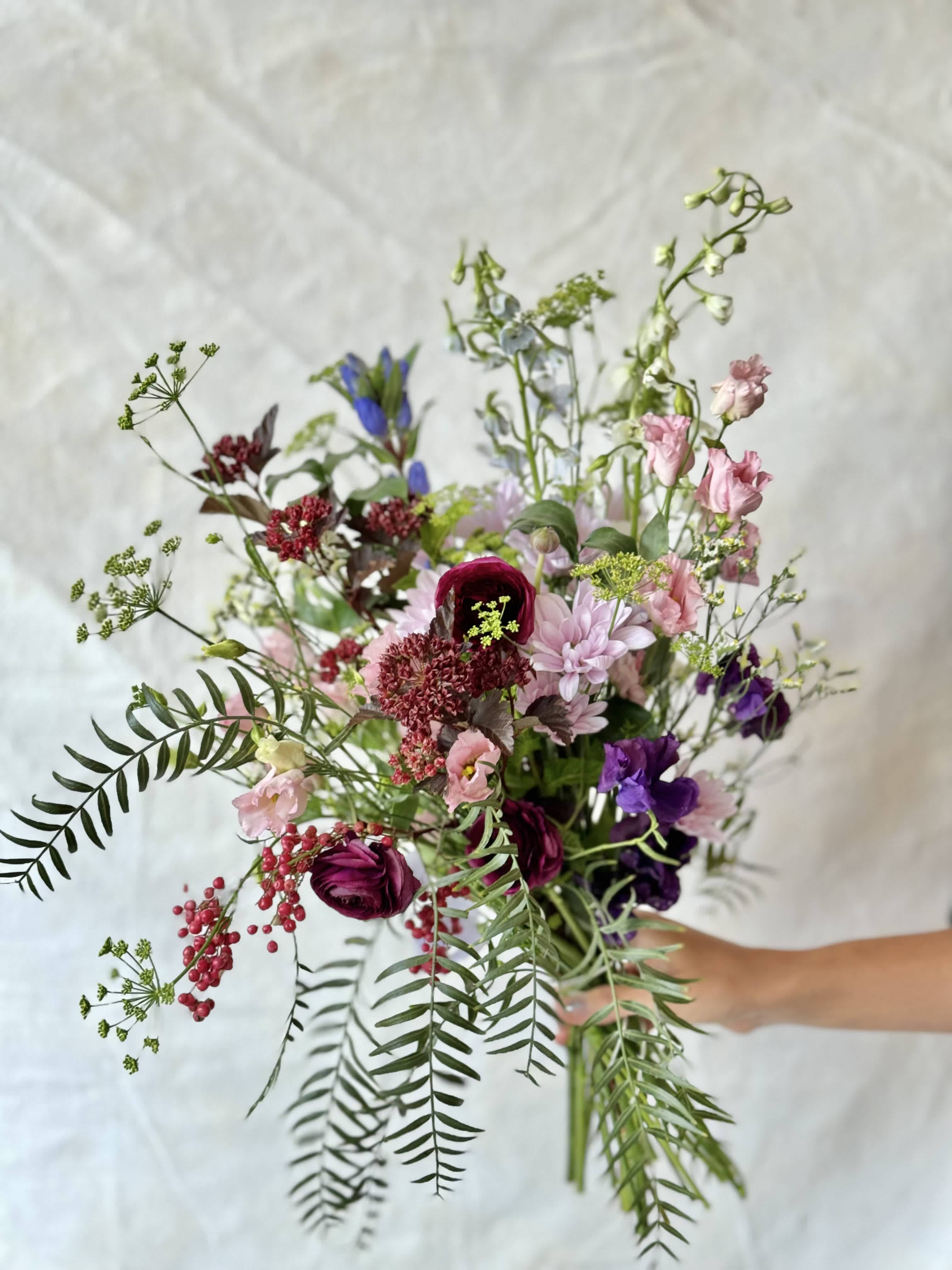 Loose bouquet of mixed pink, purple, and white flowers with airy greenery