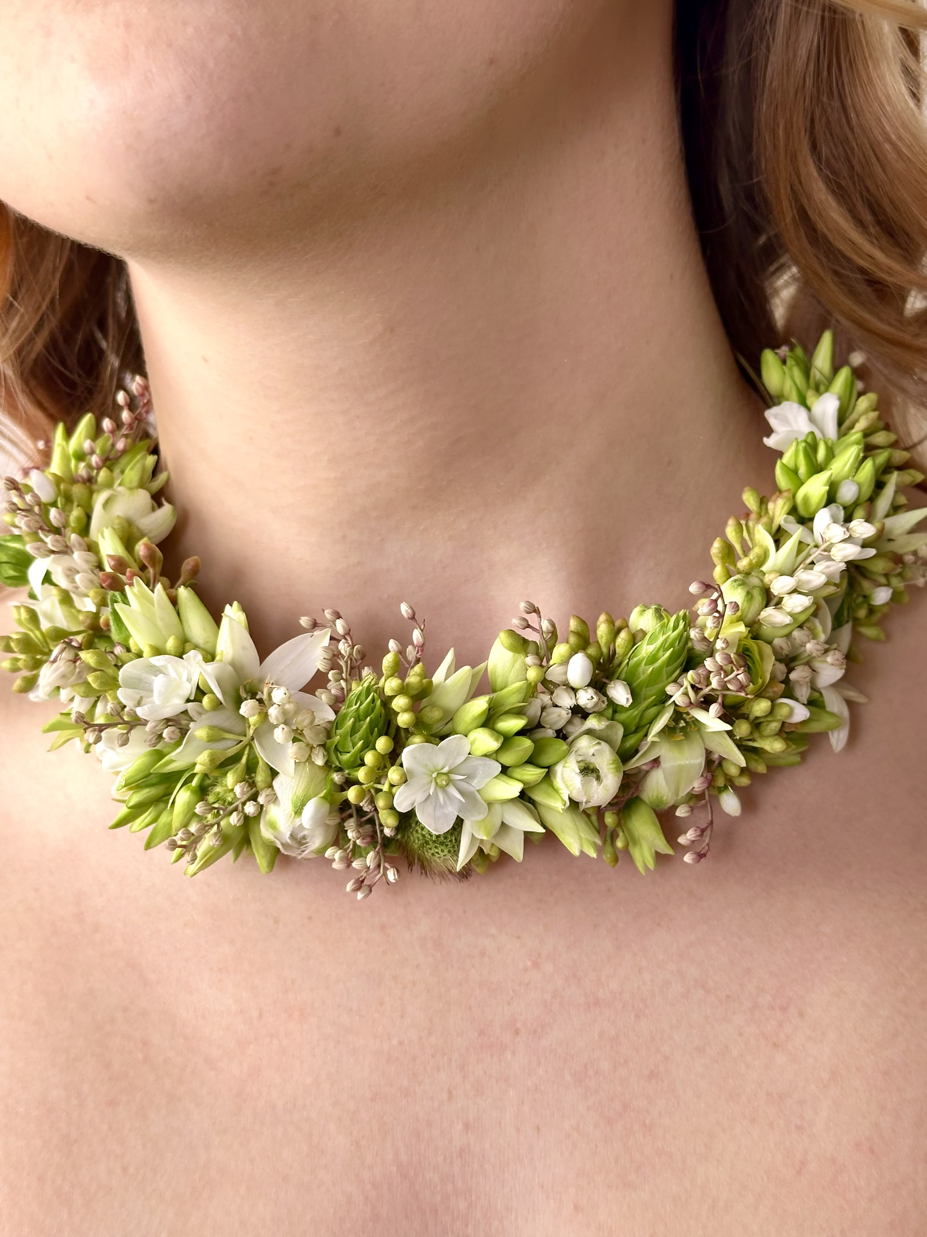 Floral necklace with white and green blossoms around the neck