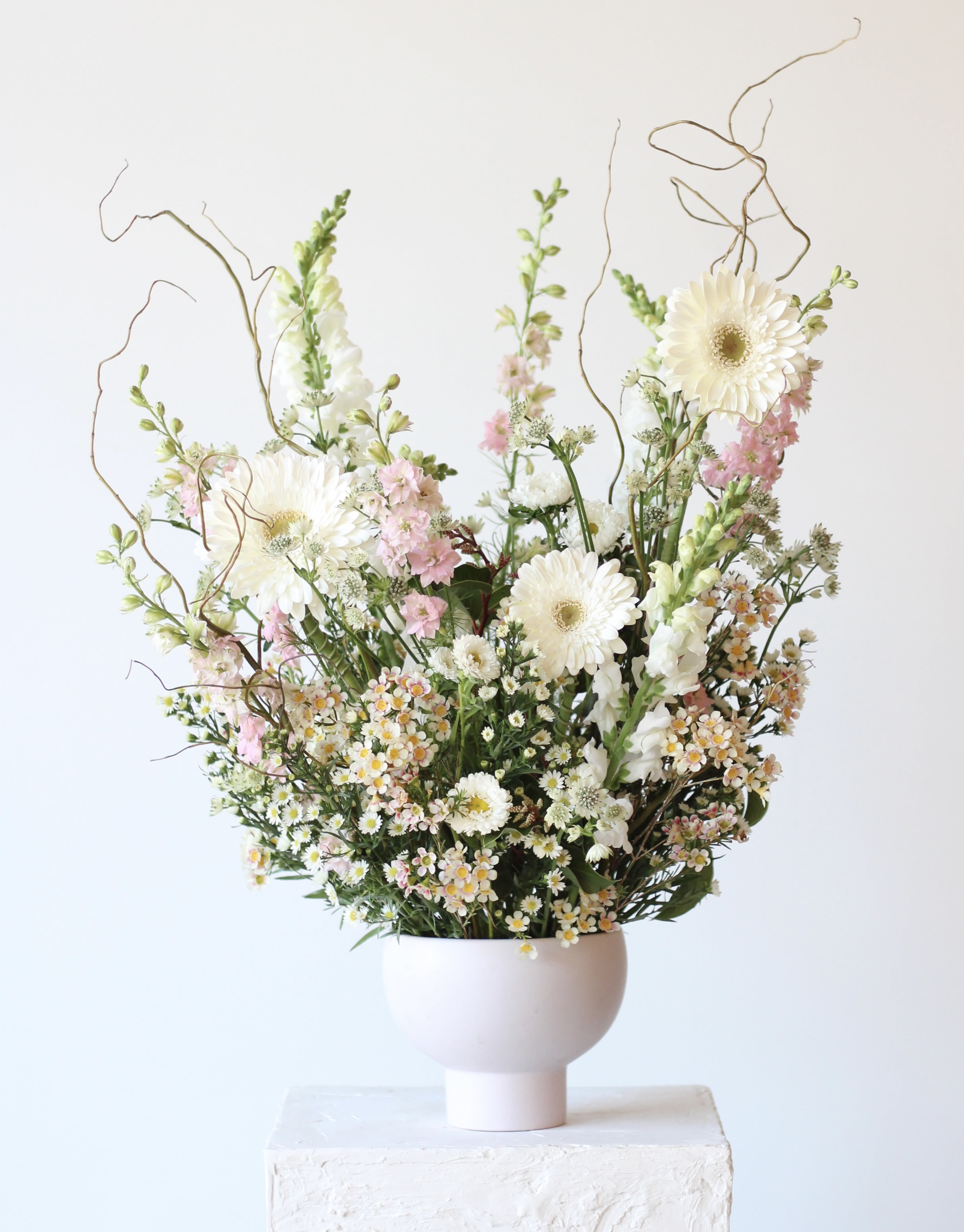Tall bouquet of white and pink flowers in a pale vase