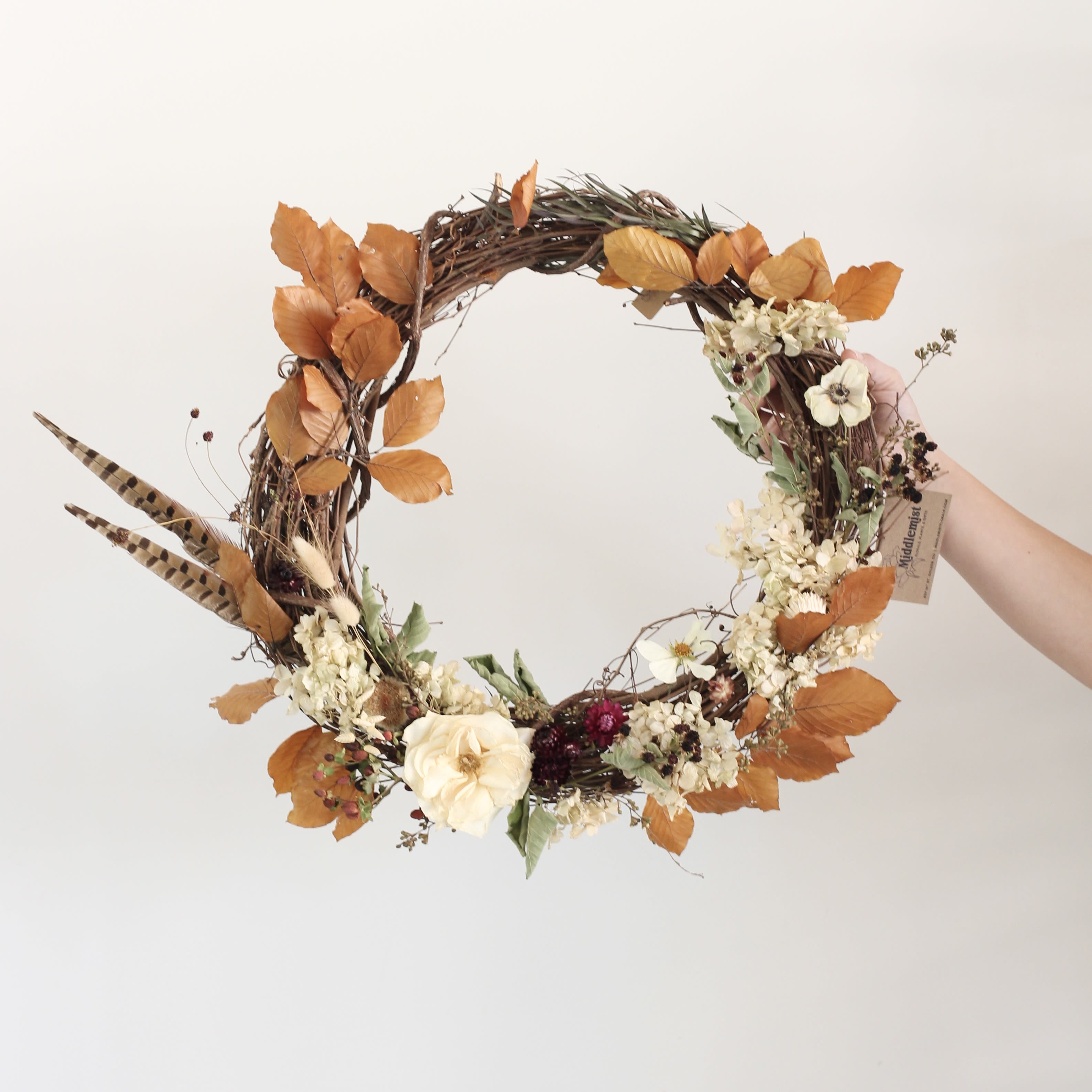Autumn wreath with cream flowers and orange leaves