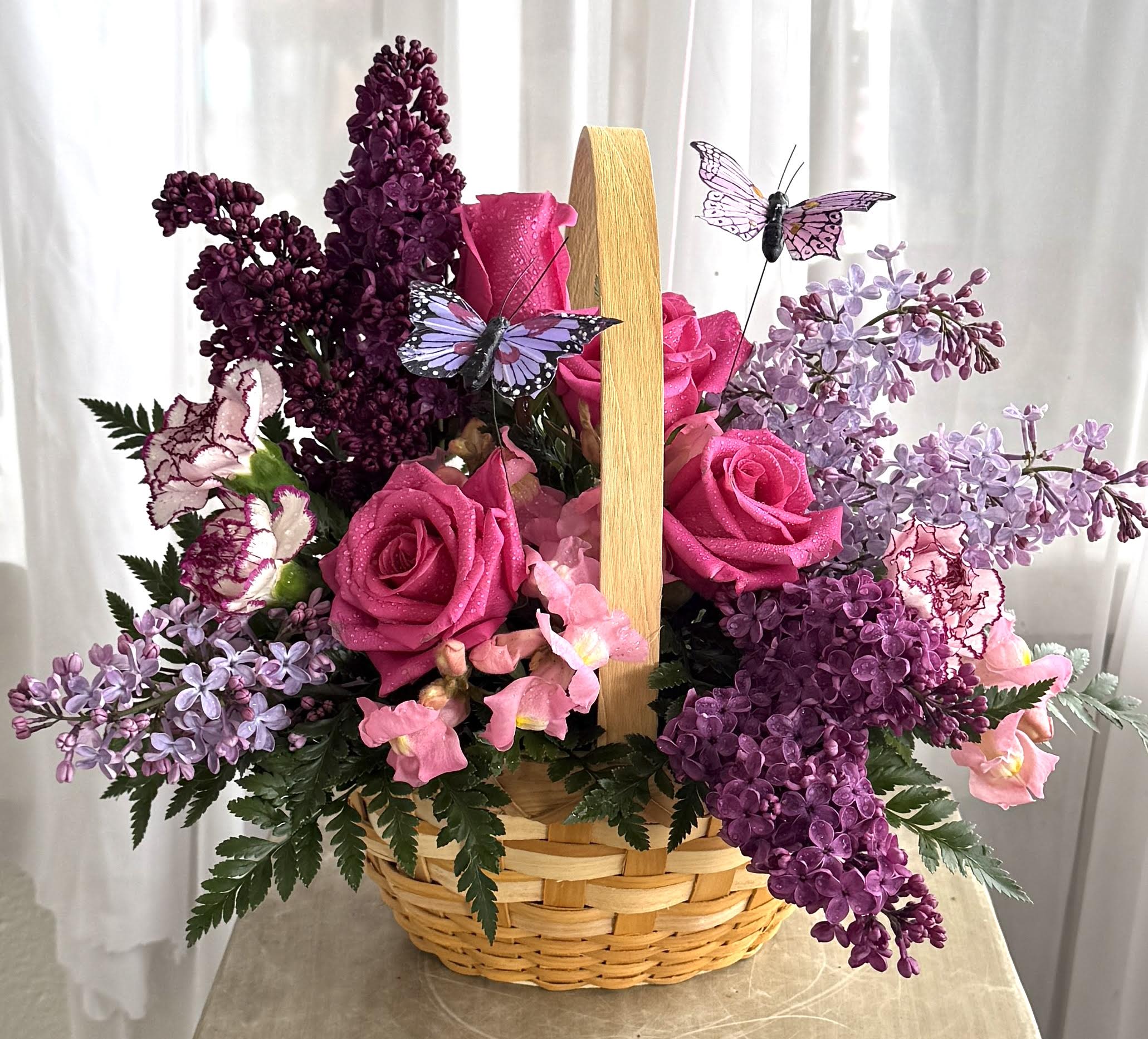 Country Basket Blooms by Teleflora - Talk about a bountiful basket! This wicker basket is overflowing with beauty and blossoms. It's no wonder two pretty butterflies have made this basket their home.  
