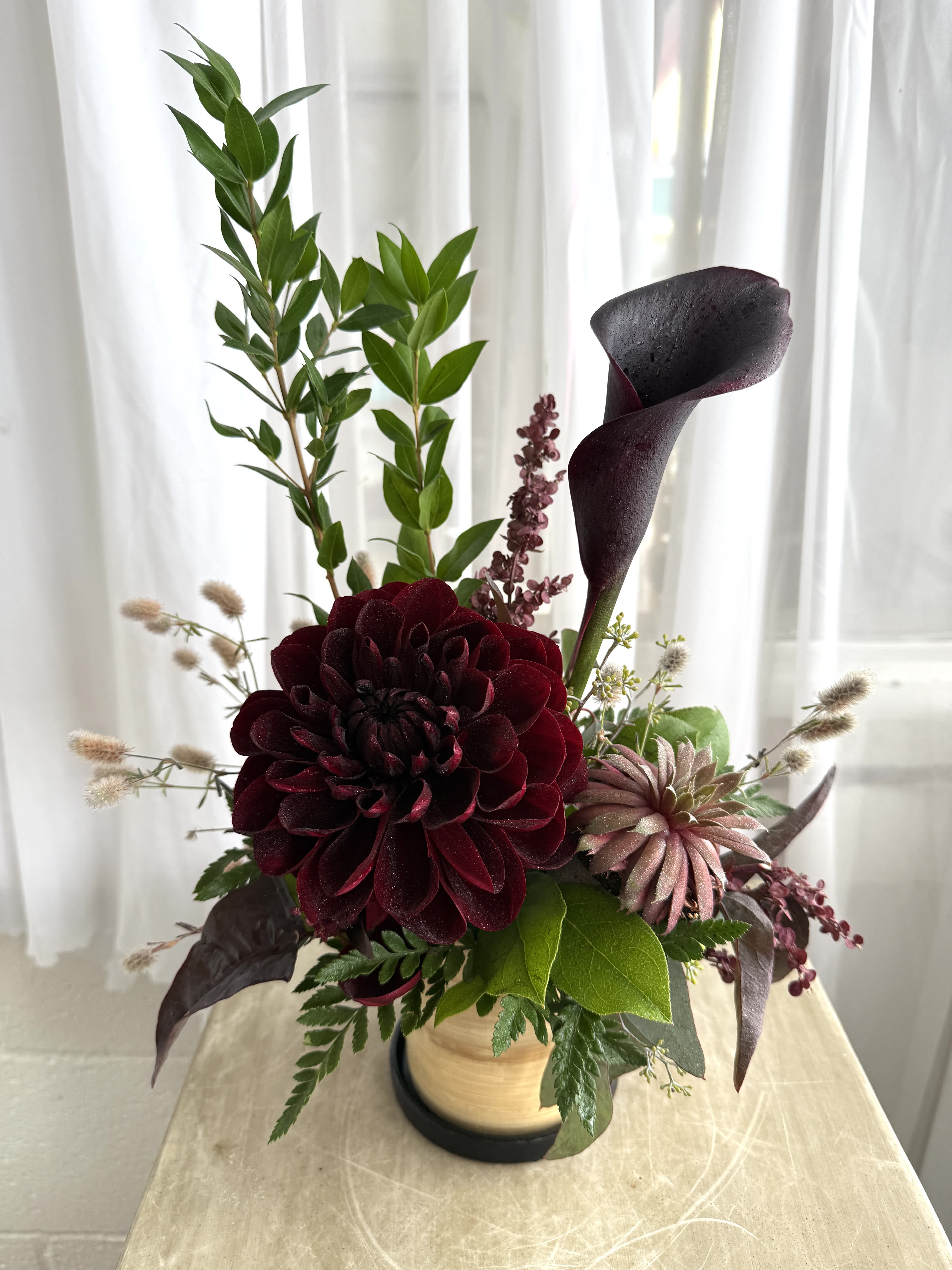 Dark burgundy floral arrangement with a black calla lily in a vase