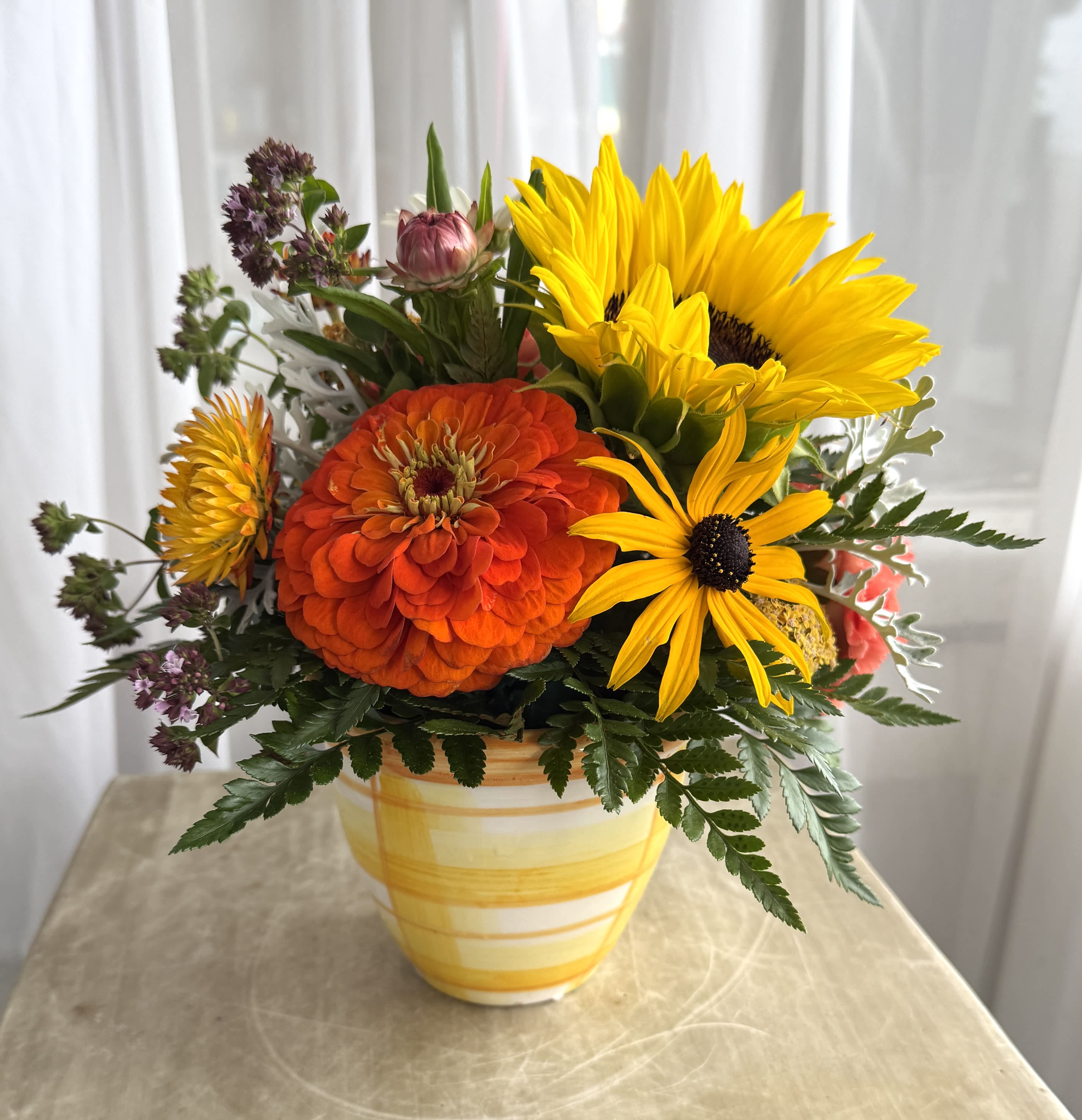 Bright yellow and orange flowers arranged in a striped ceramic vase