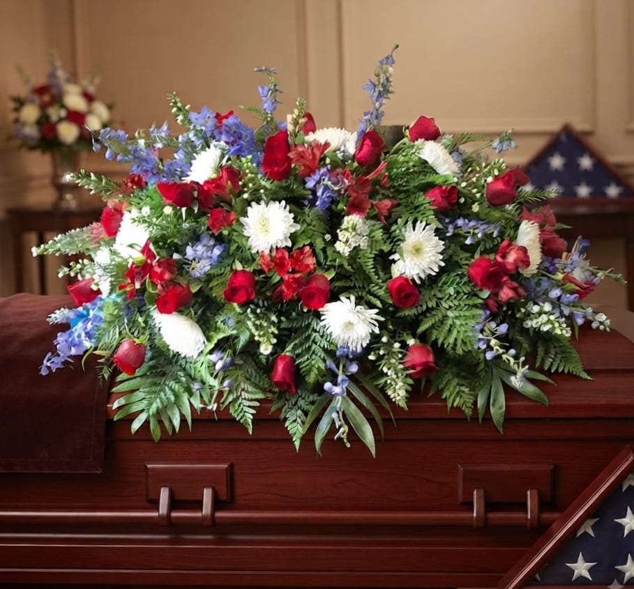 Red, white, and blue floral spray arranged on a wooden casket
