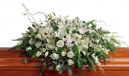 Large white rose and lily casket spray on a polished wood casket