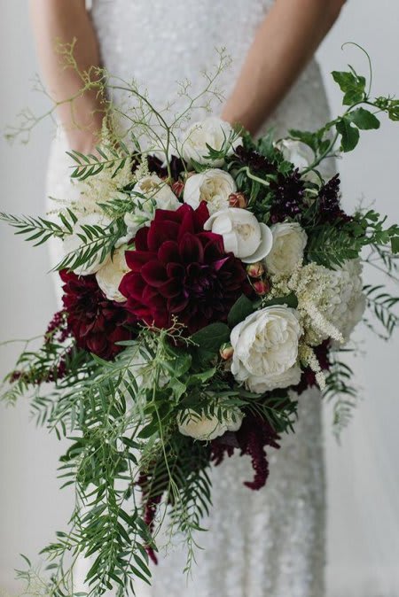 Bride holding a cascading bouquet of white and deep red flowers