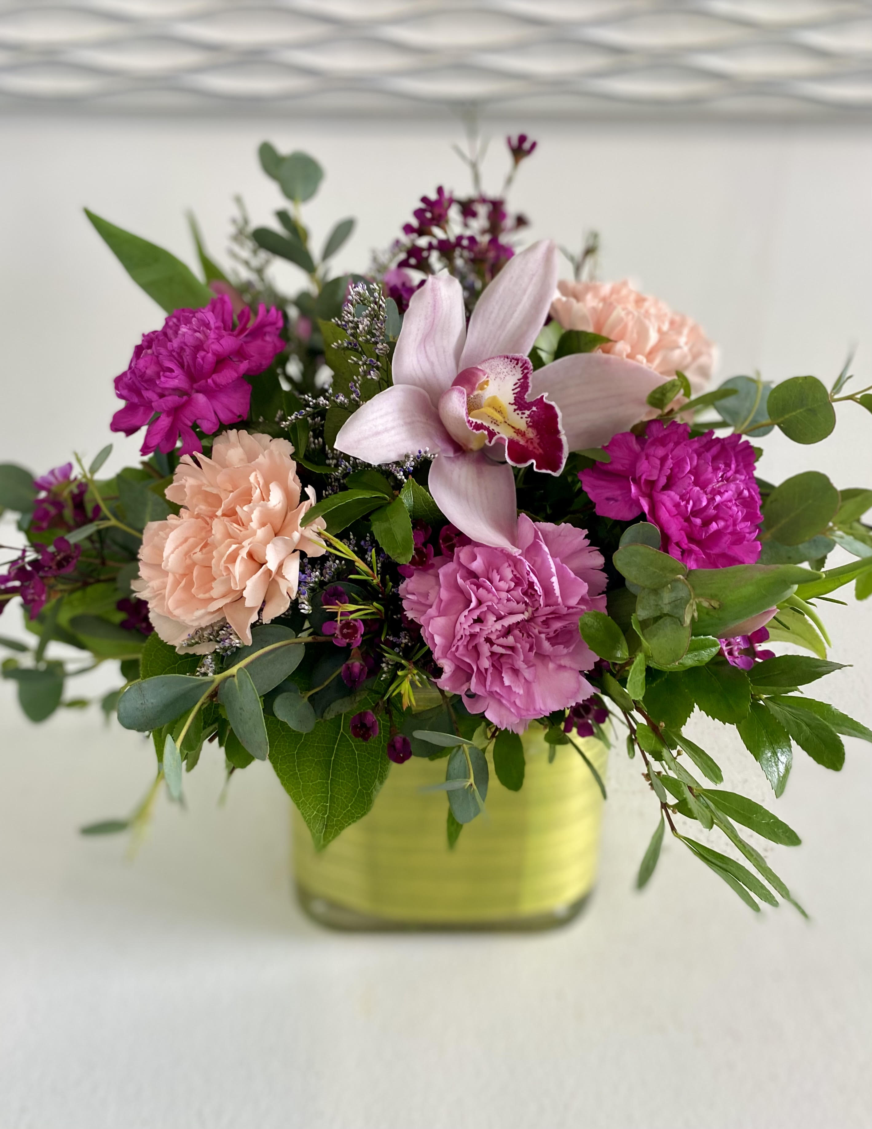Pink and peach floral arrangement in a square glass vase