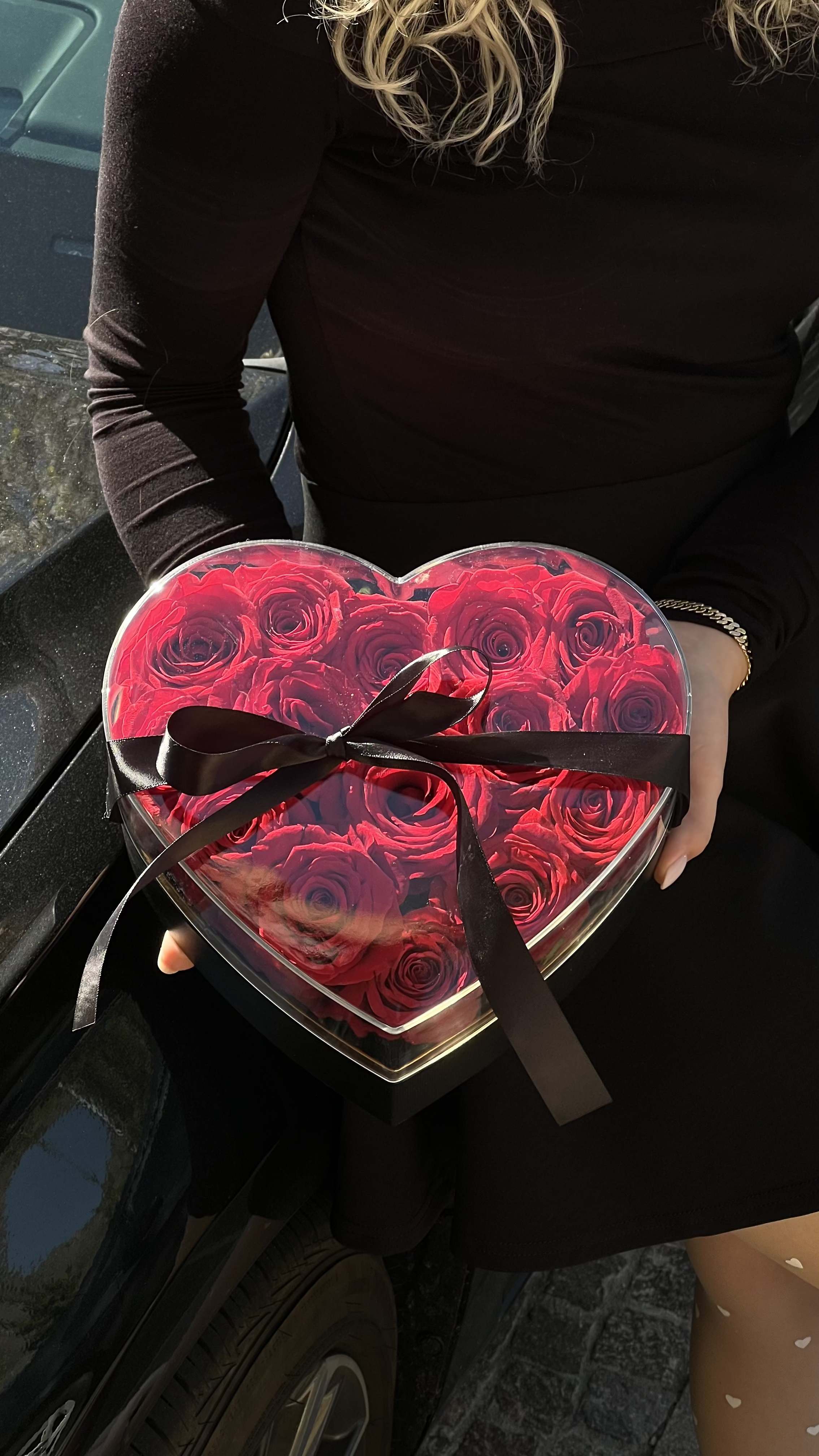 Heart-shaped box of red roses tied with a black ribbon