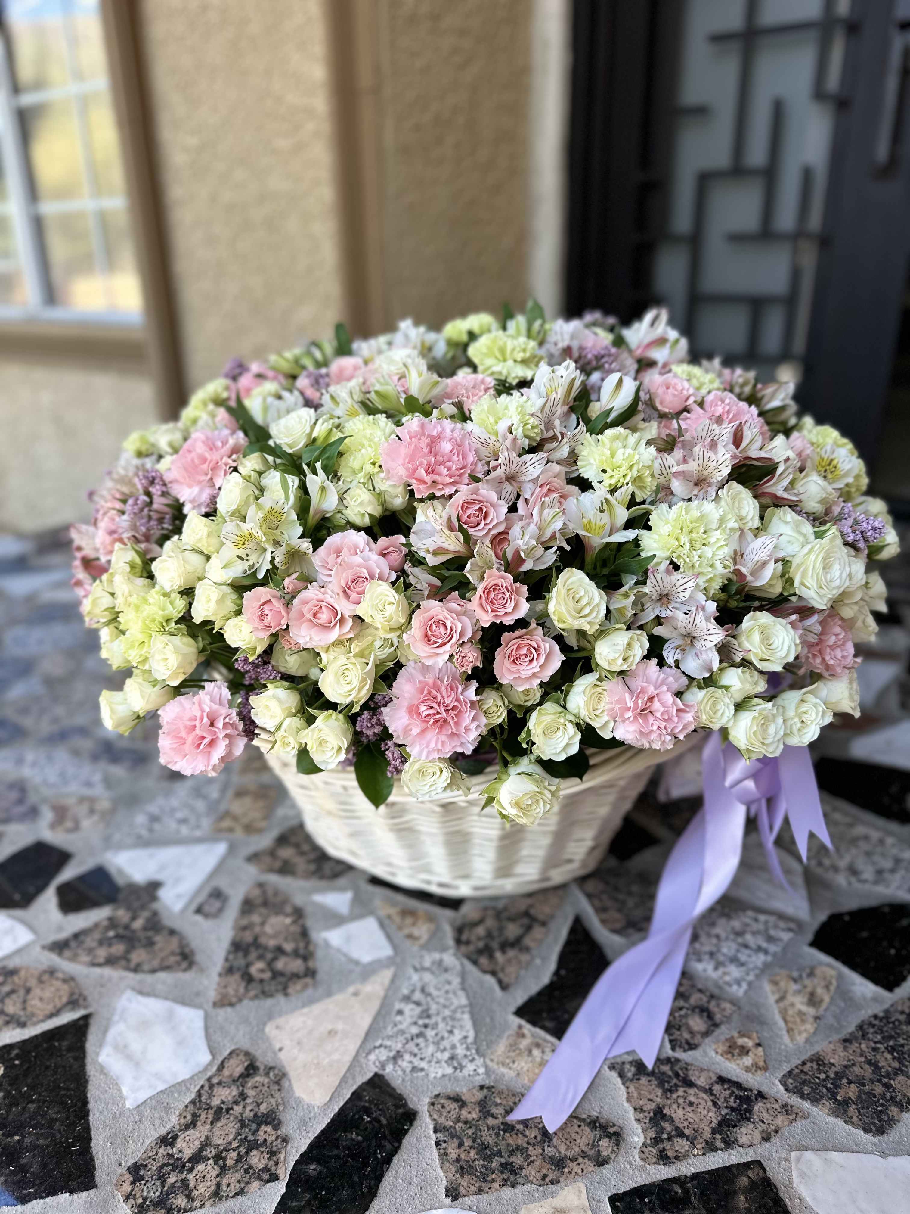 Large basket of pink and white flowers with a lavender ribbon