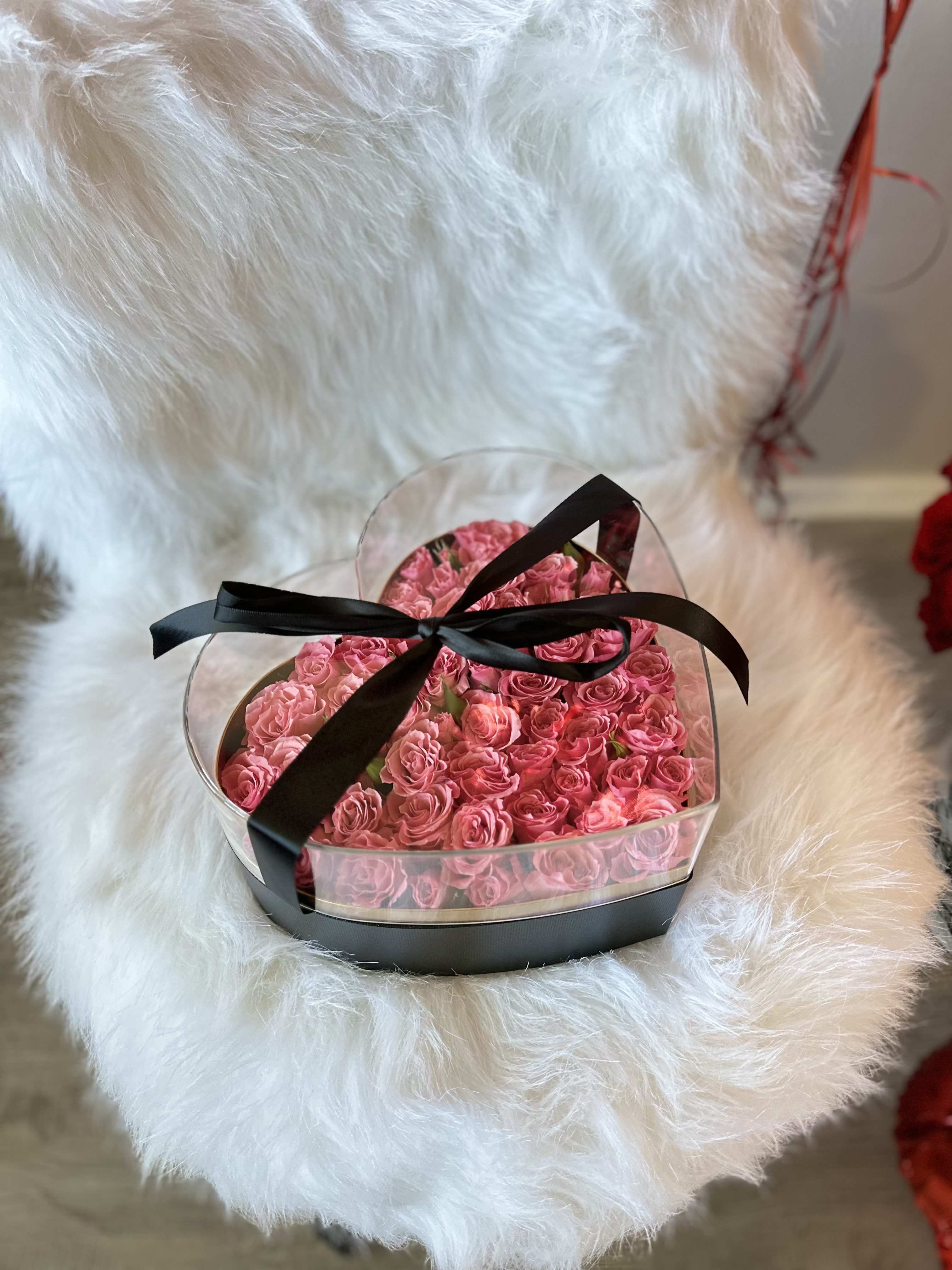 Heart-shaped box of pink roses tied with a black ribbon