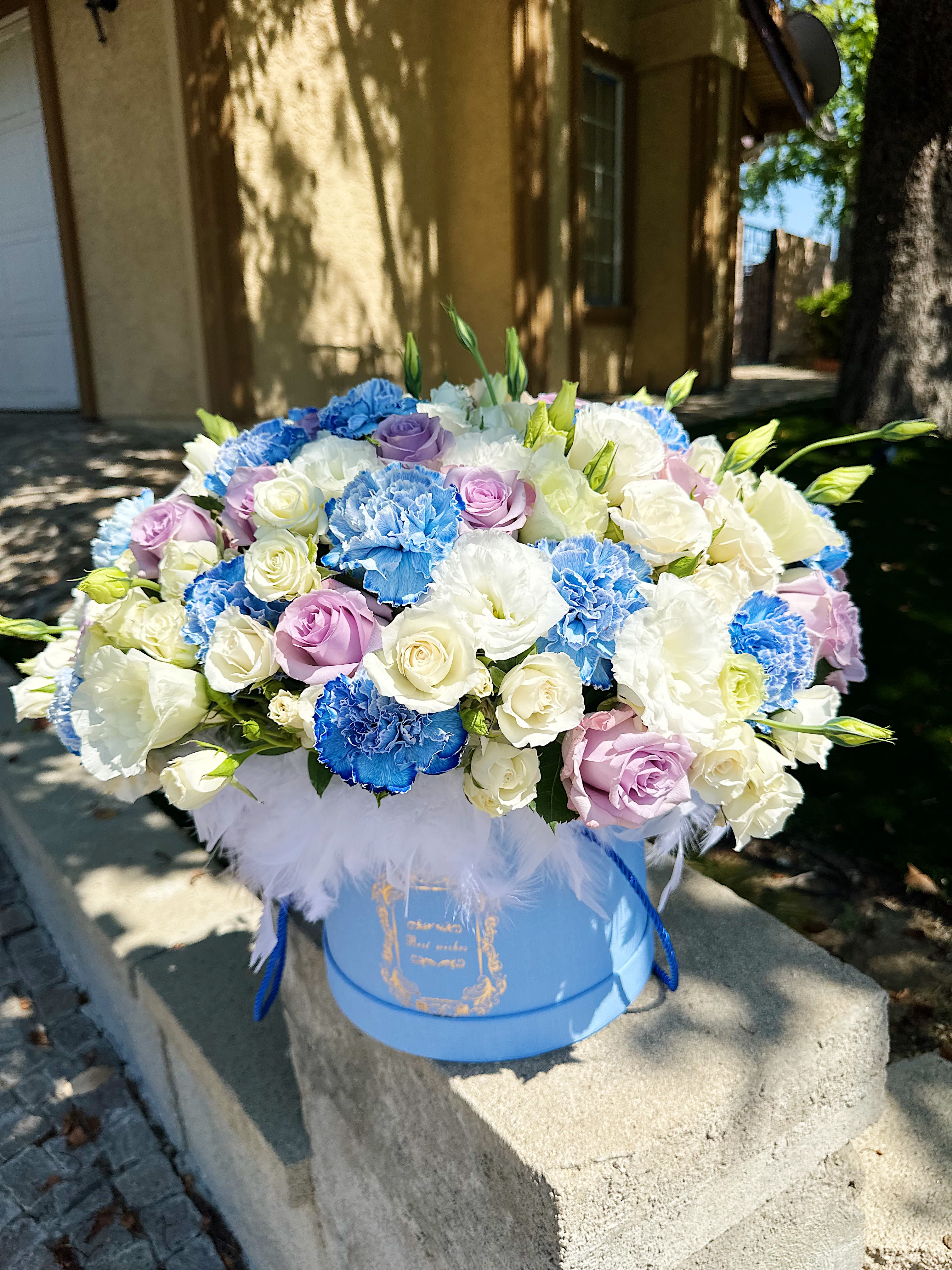 Blue, white, and lavender bouquet in a round blue box
