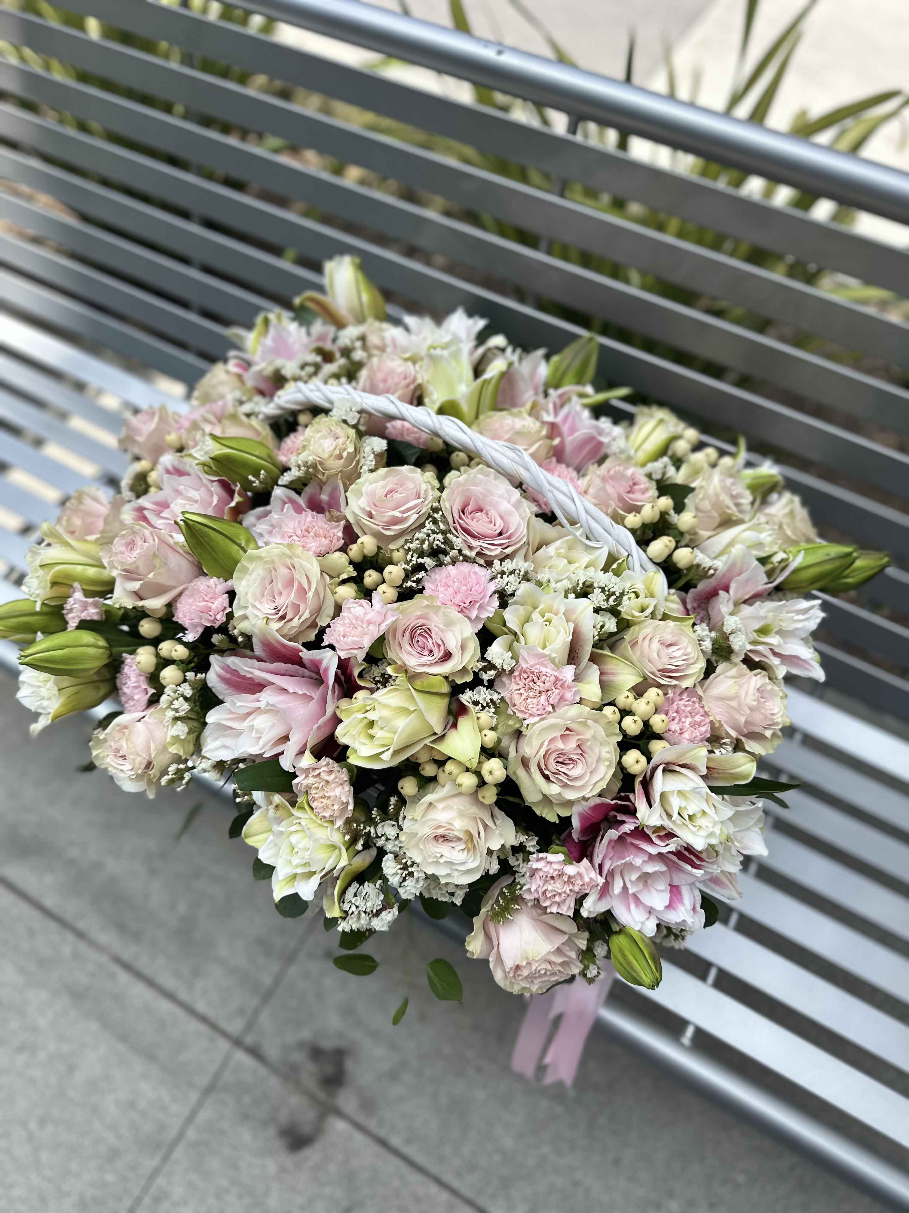 Handheld bouquet of pale pink and white flowers with a braided handle