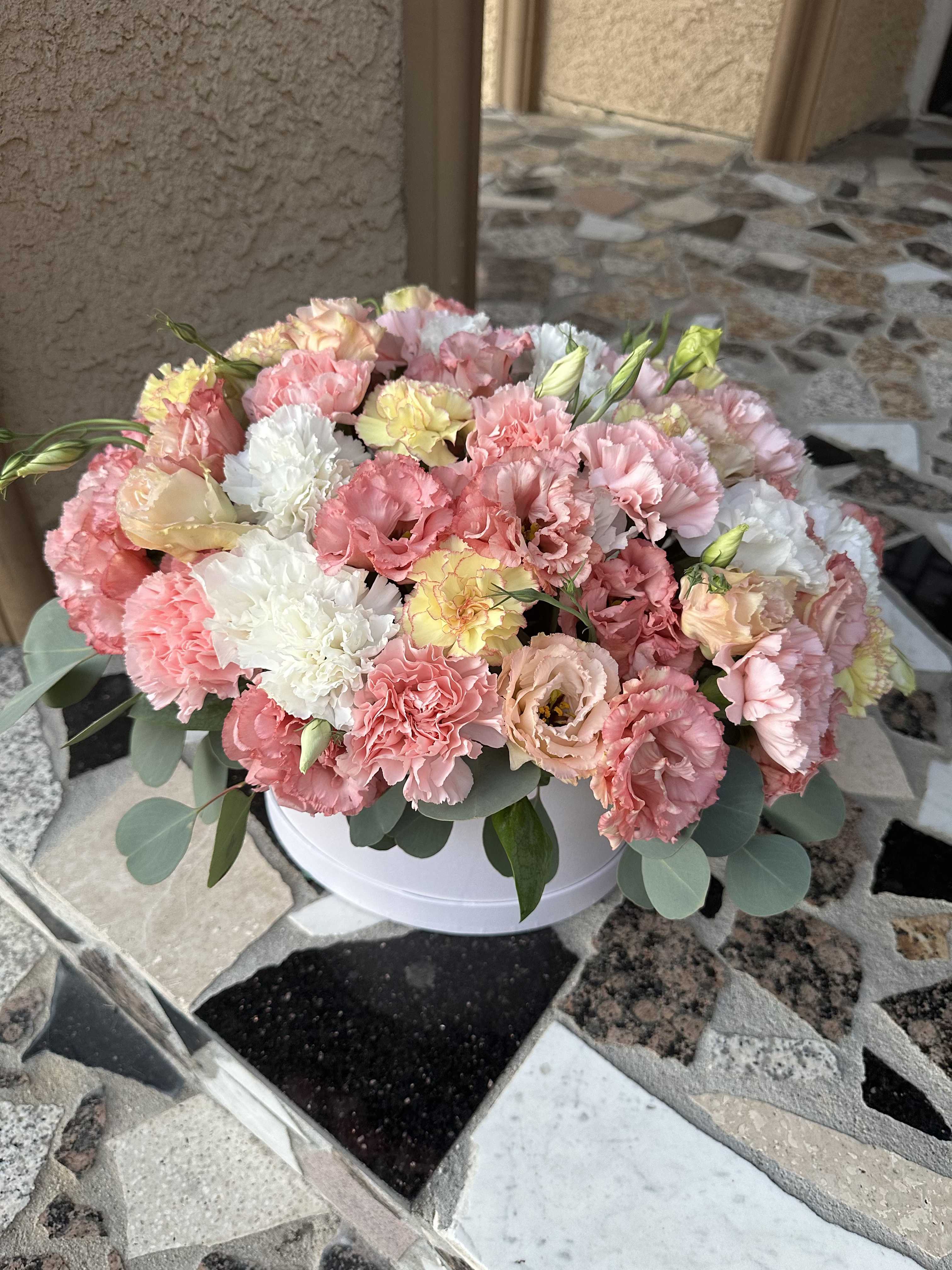 Pink and white carnations arranged in a white round box