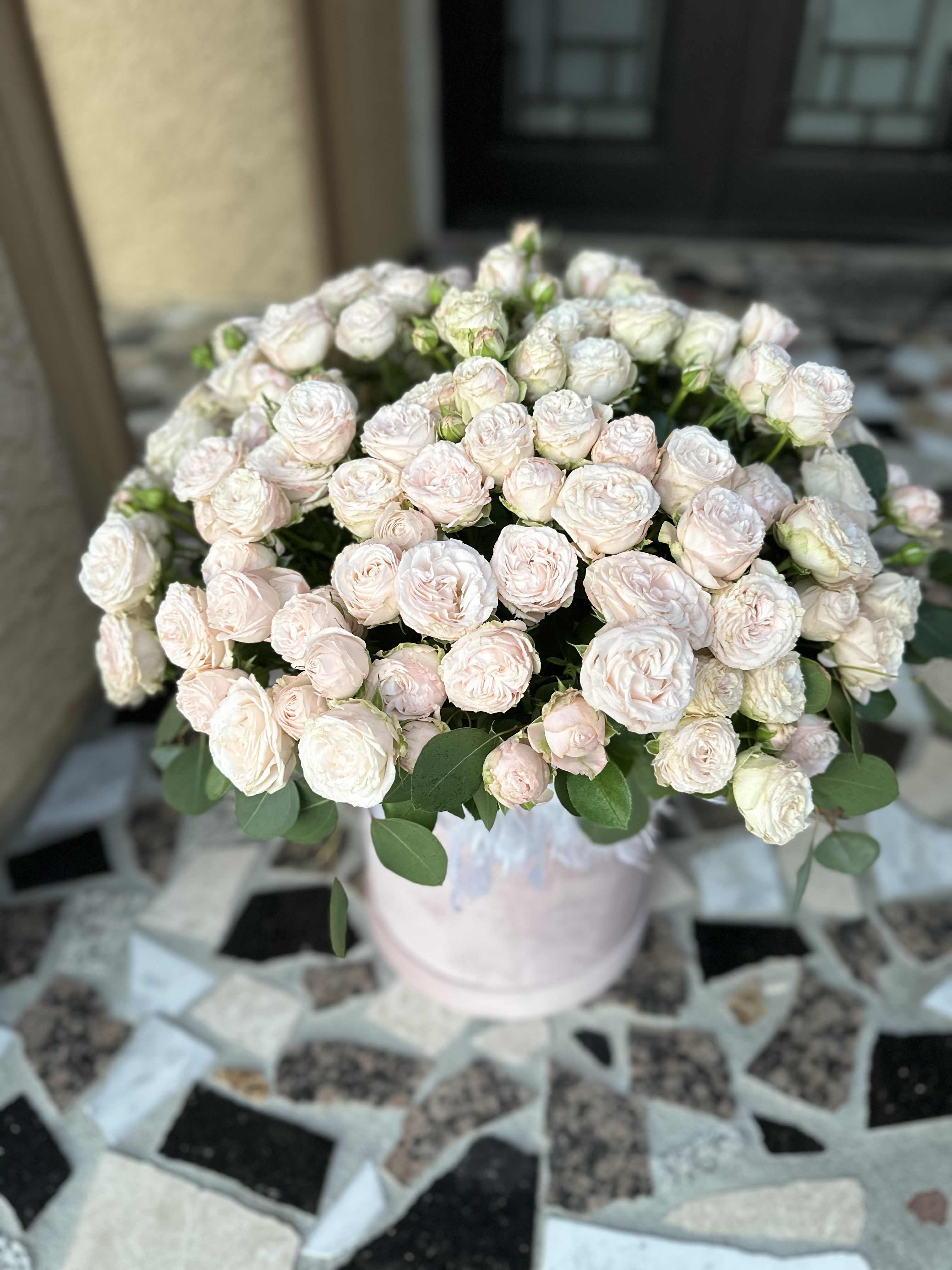 Bouquet of pale pink spray roses in a light pink vase