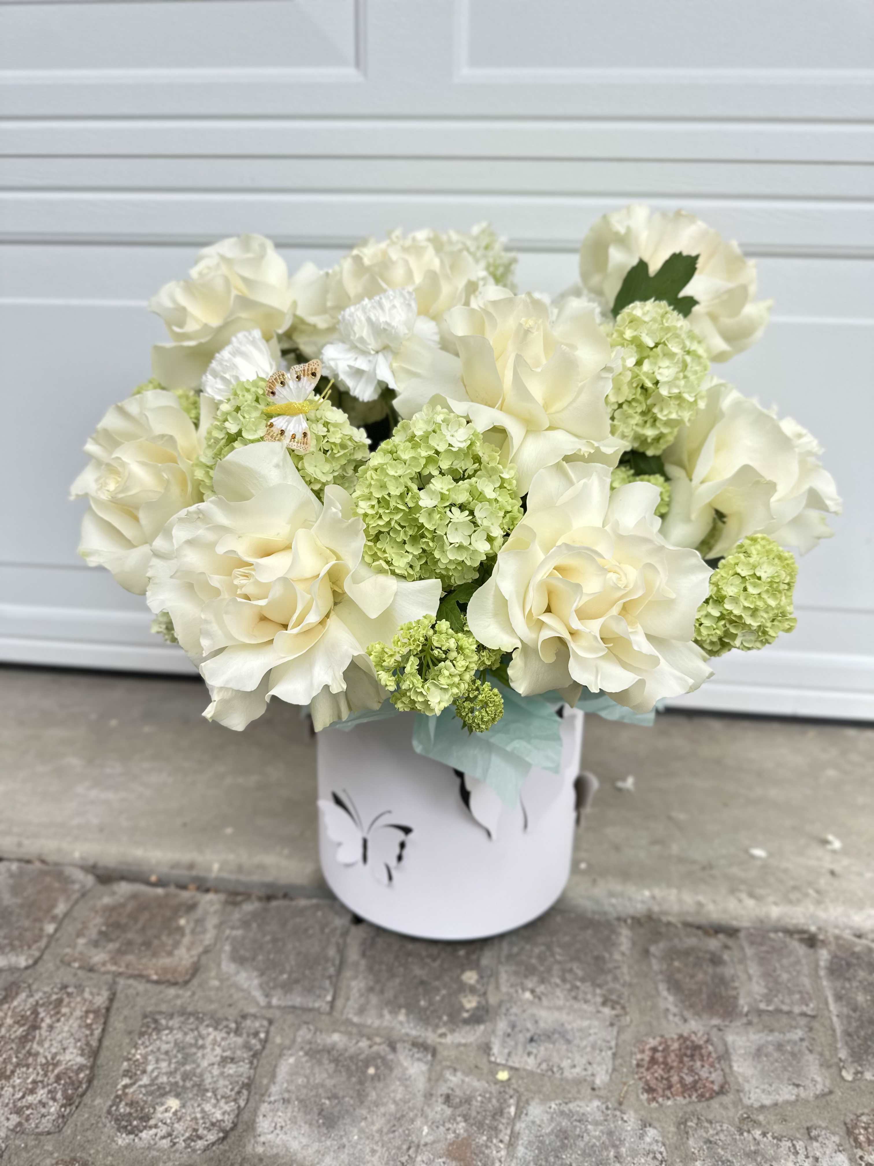 Cream roses and green hydrangeas in a white container