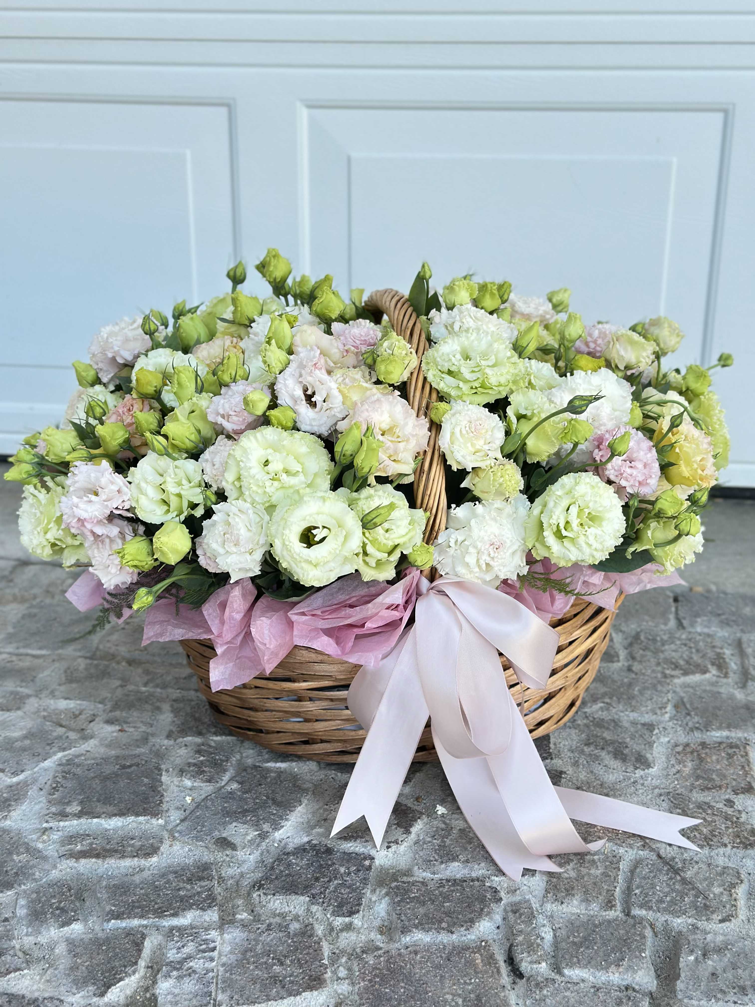 Basket of pale pink and white flowers with a ribbon bow