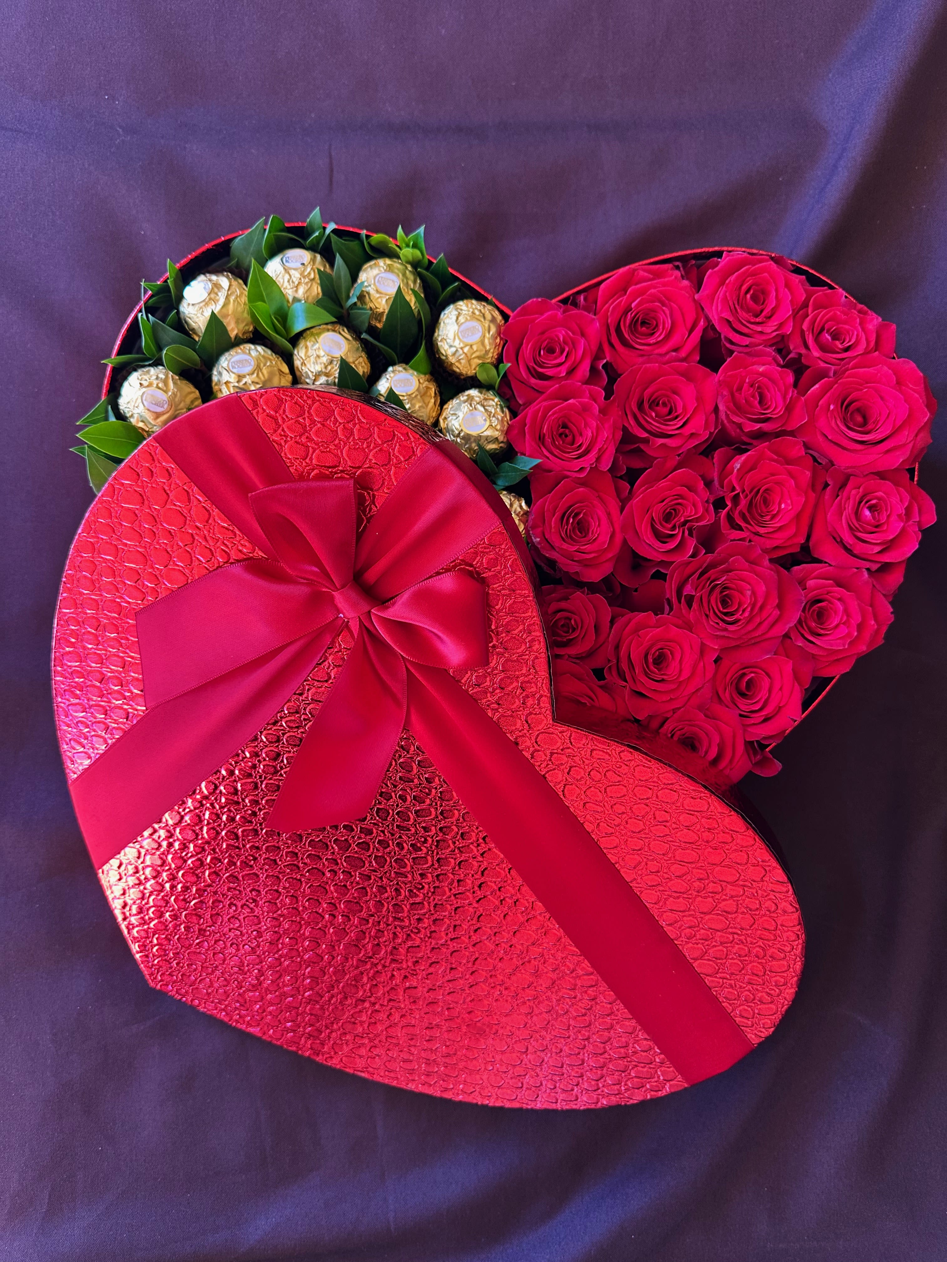 Heart-shaped box with red roses and gold-wrapped chocolates tied with a ribbon